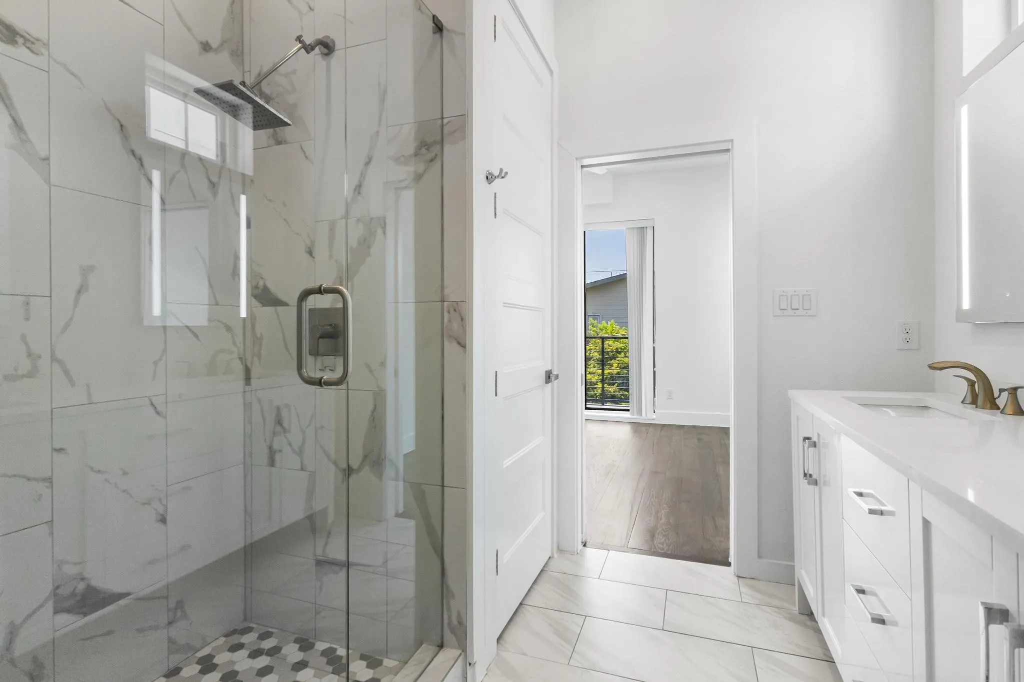 Glass-enclosed shower with a rainfall showerhead, large format wall tiling, and hexagonal floor tiling