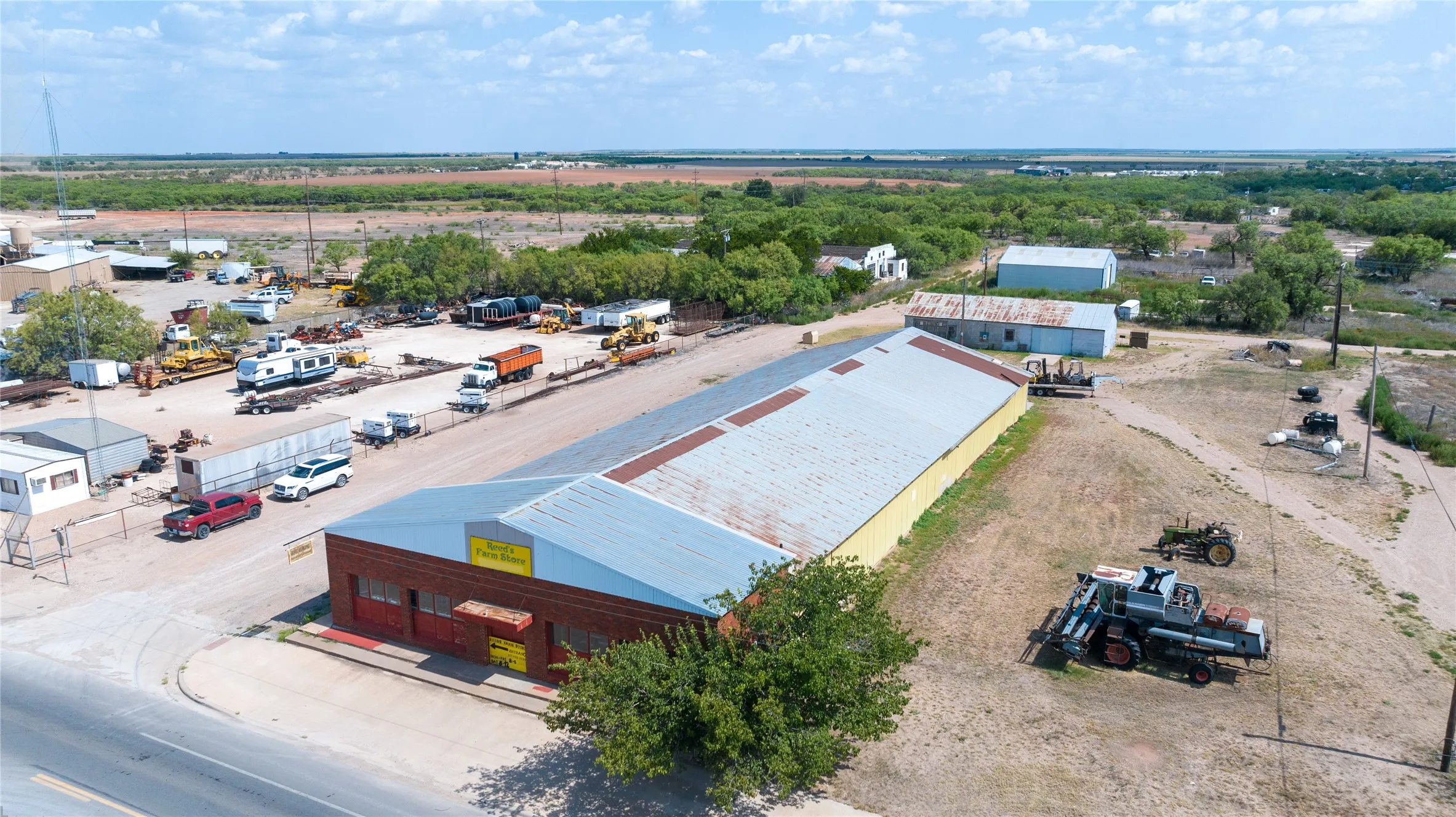Large commercial building with brick facade, metal roofing, and adjacent open-air lot