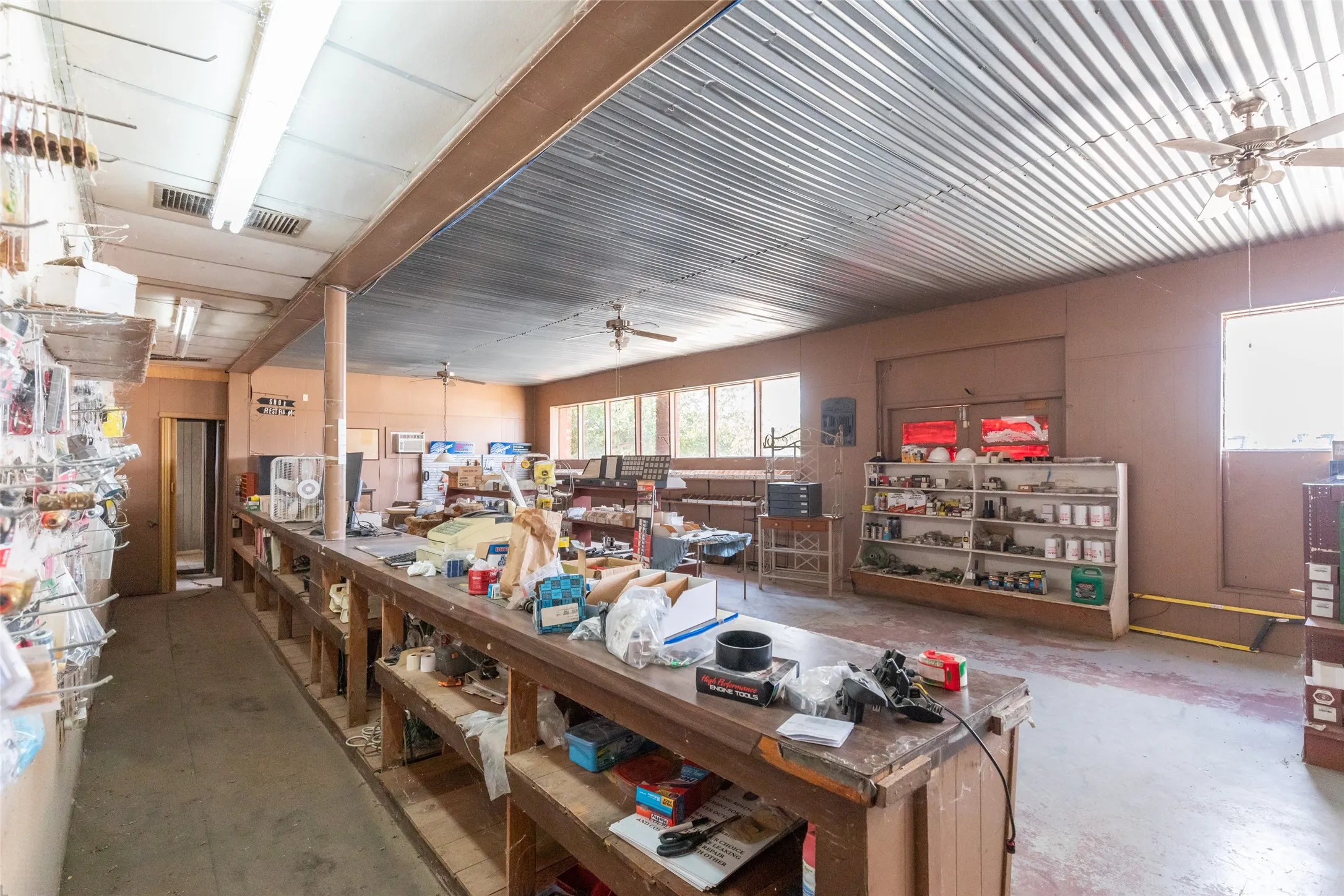 Corrugated metal ceiling, recessed fluorescent lighting, multiple windows, and exposed ceiling beams