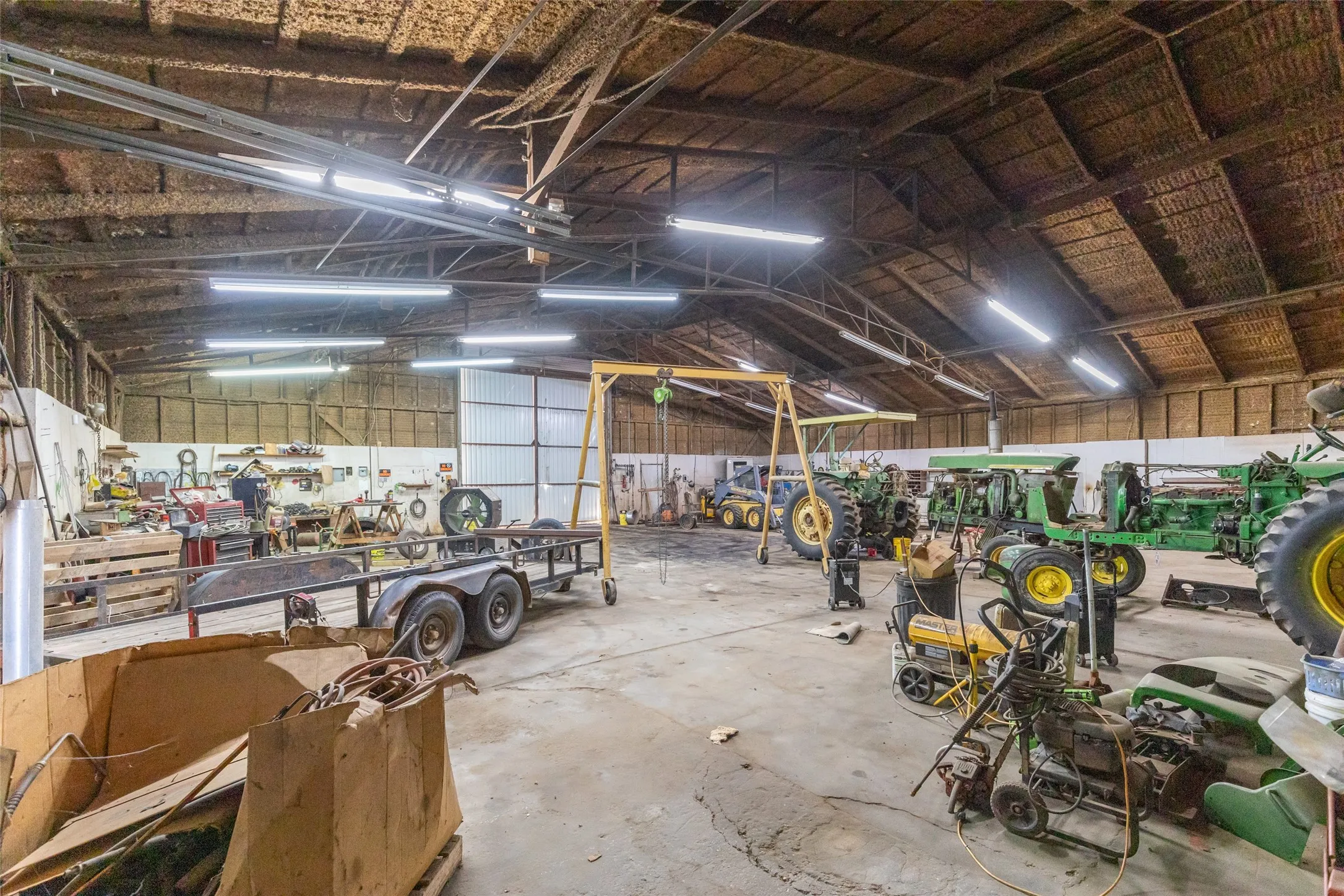 Expansive interior space featuring a high-pitched ceiling, exposed wood beams, and concrete flooring
