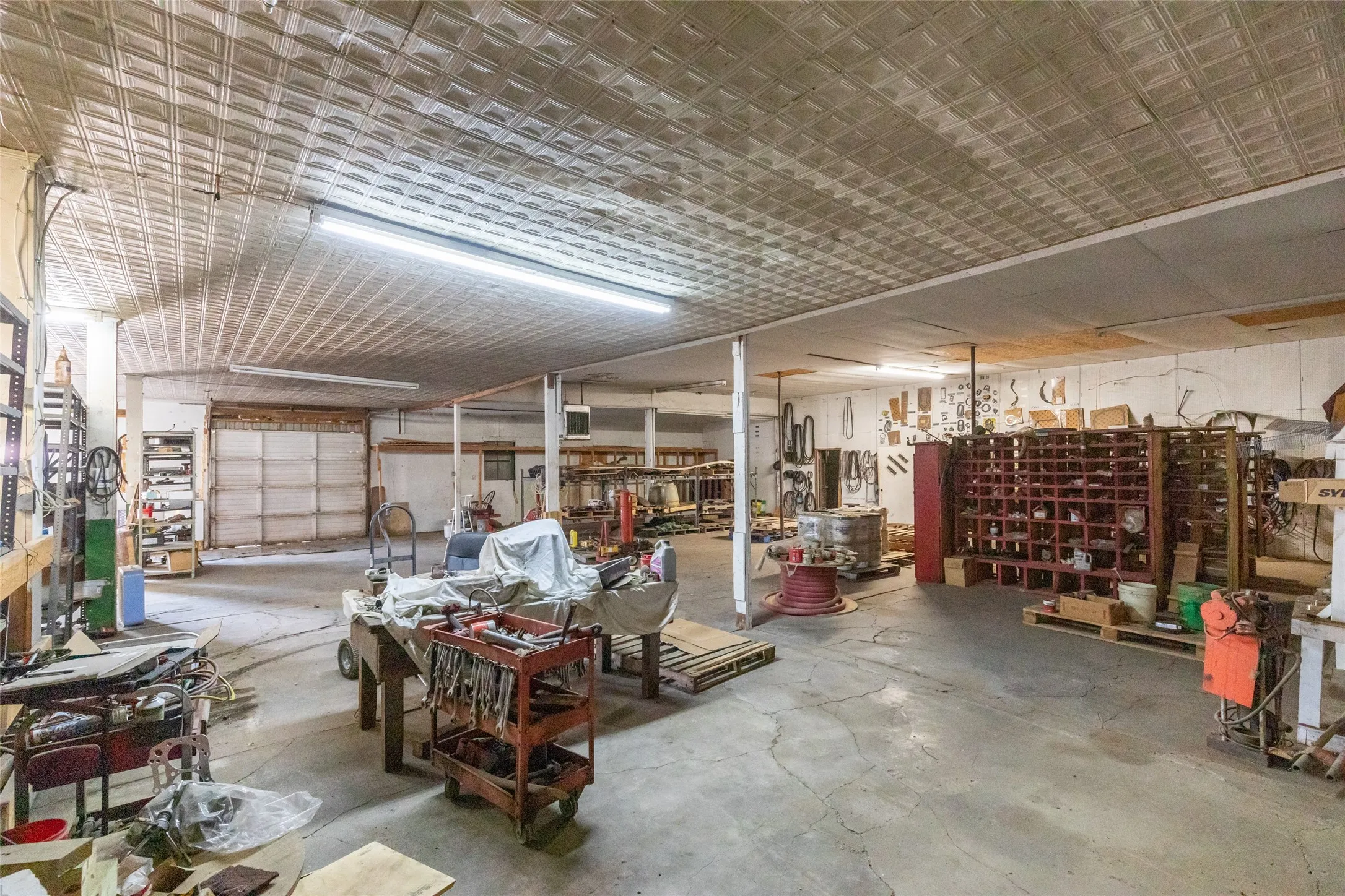 Expansive open space featuring a patterned ceiling, concrete flooring, and multiple support columns