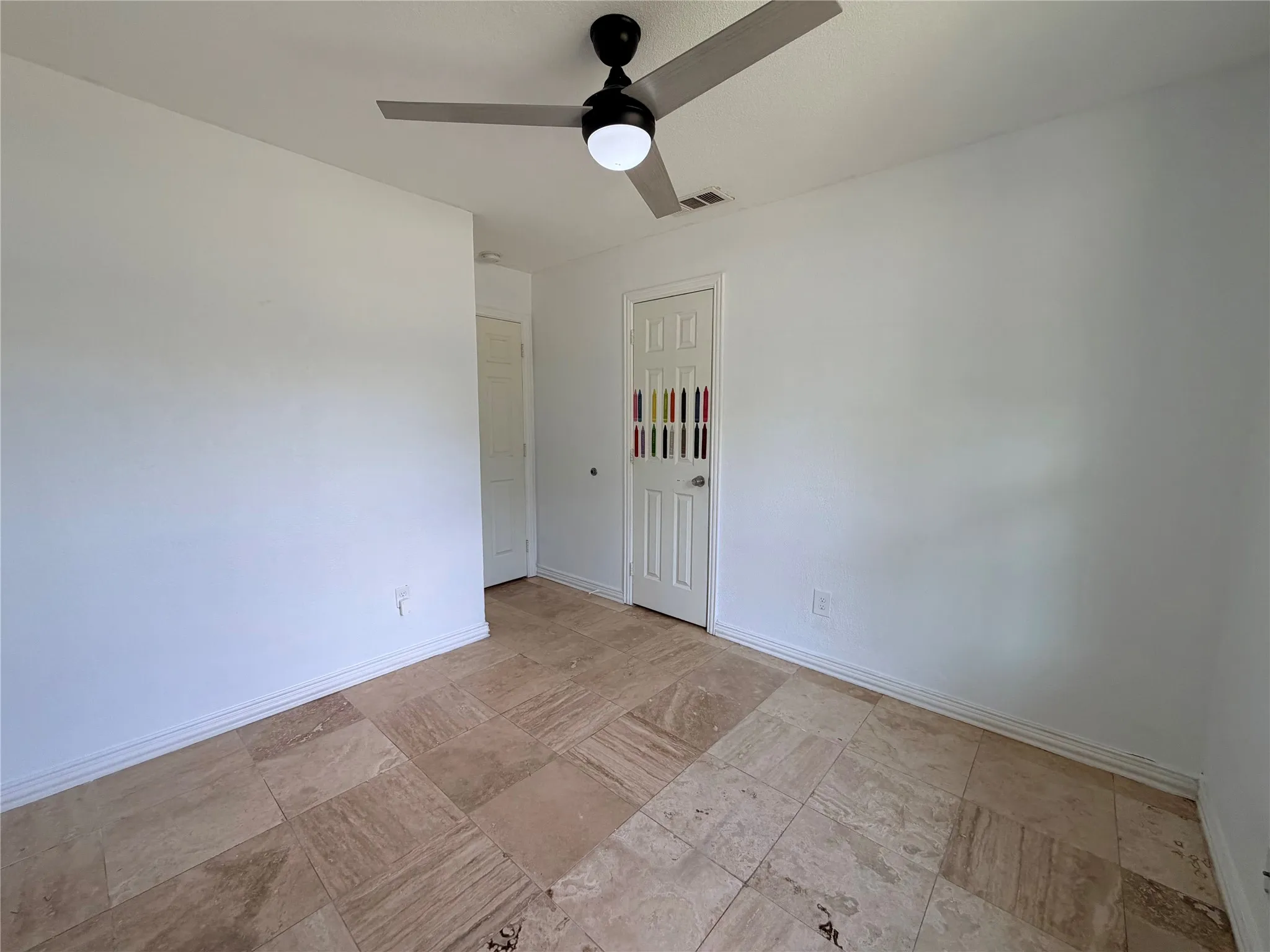 Spacious room with large-format tile flooring, a modern ceiling fan, and white walls