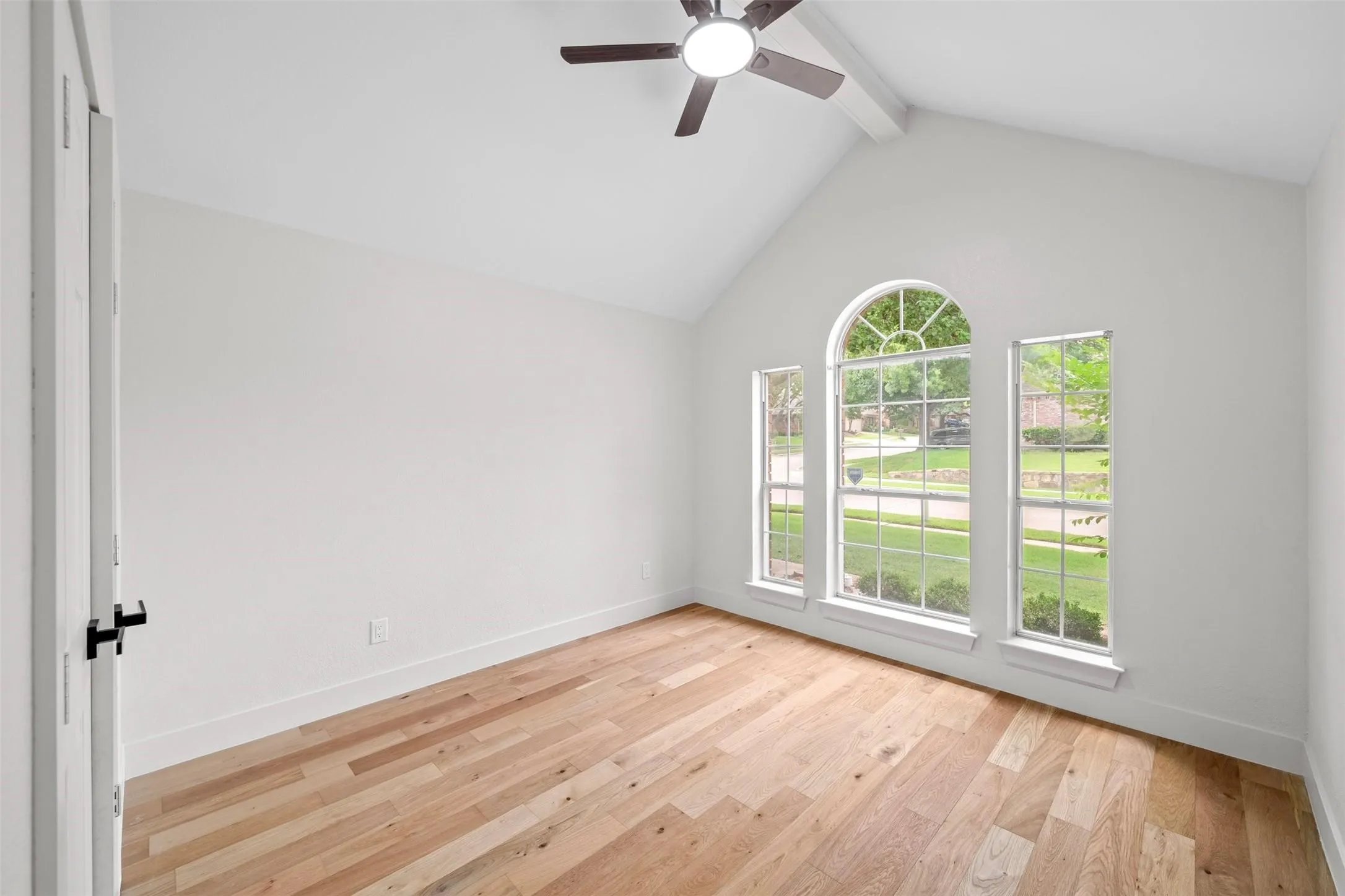 Vaulted ceiling with exposed beam, wood-finish flooring, and a ceiling fan