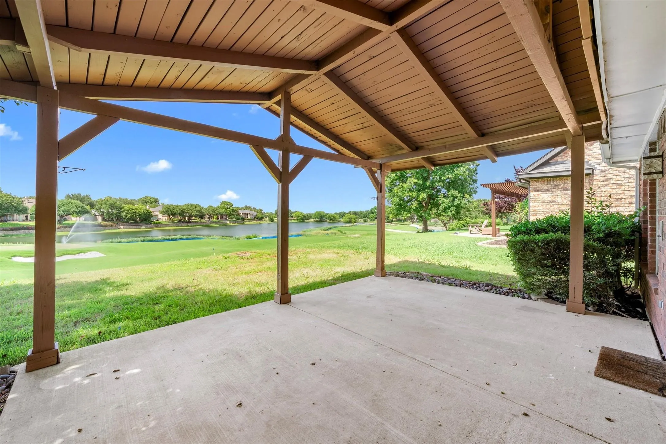 Covered concrete patio with wood-tone ceiling and structural supports