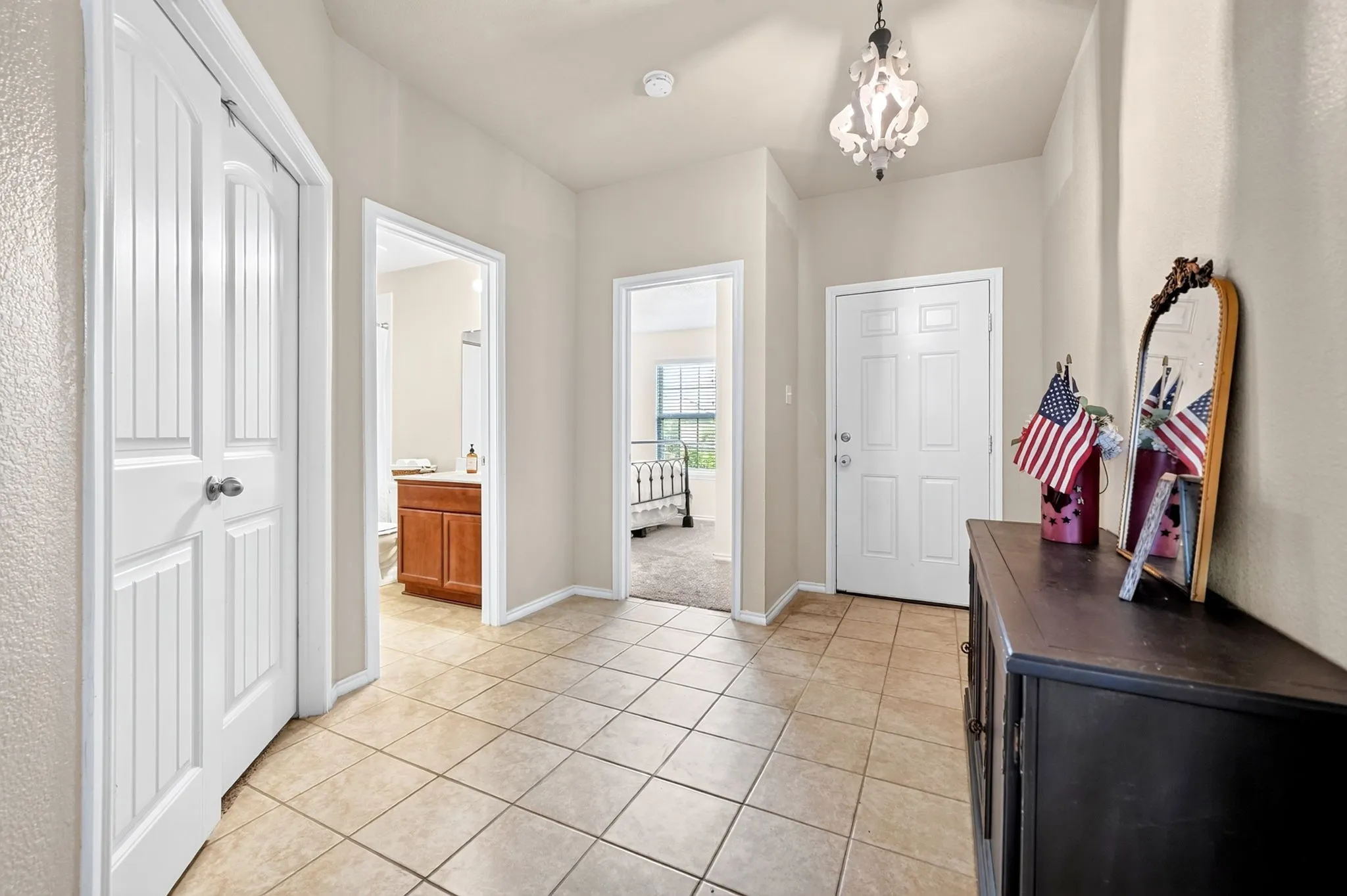 Neutral-toned tile flooring, recessed lighting, and a decorative ceiling fixture illuminate the entry area