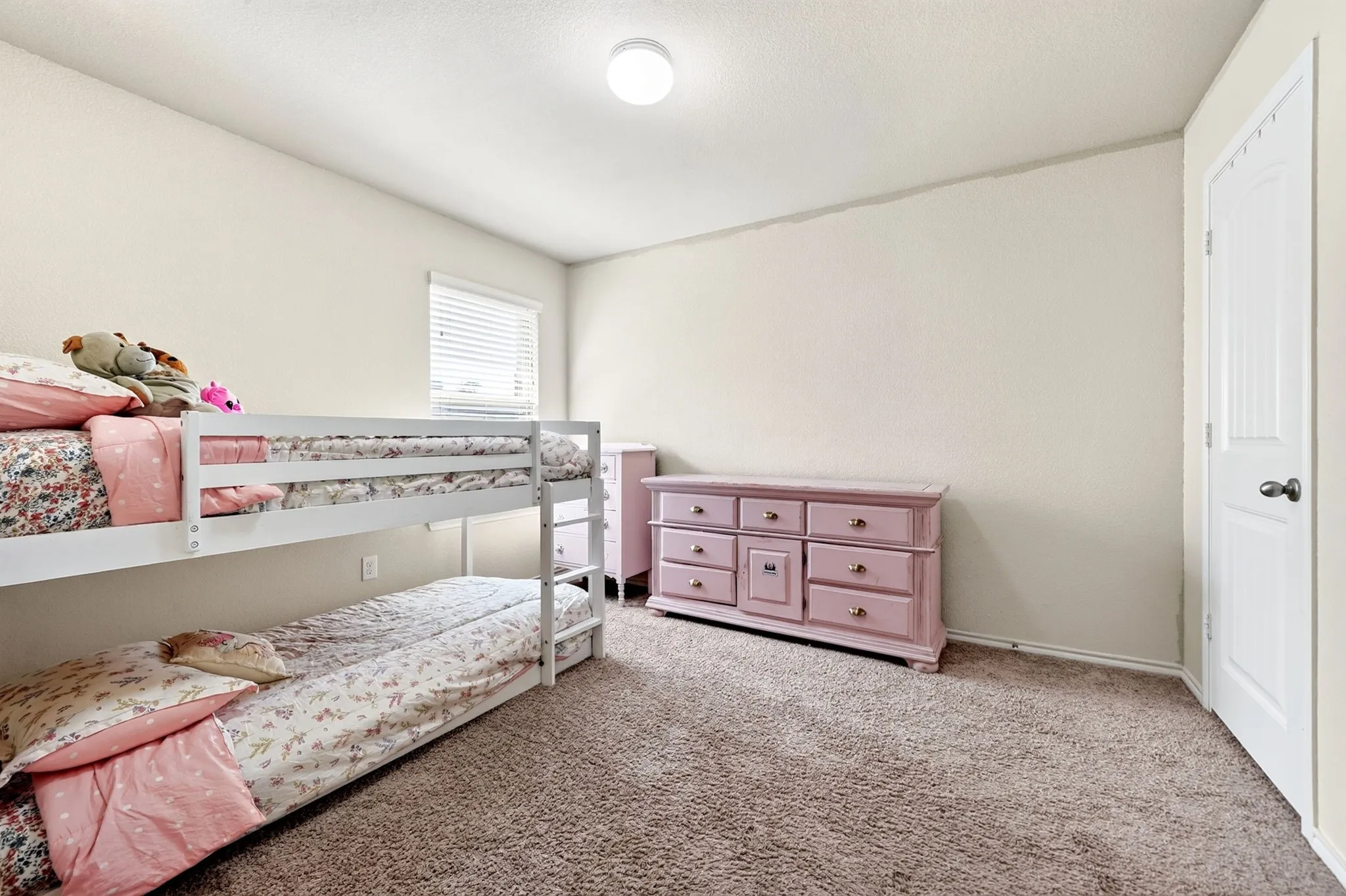 Neutral wall paint, textured carpet, and a window with horizontal blinds