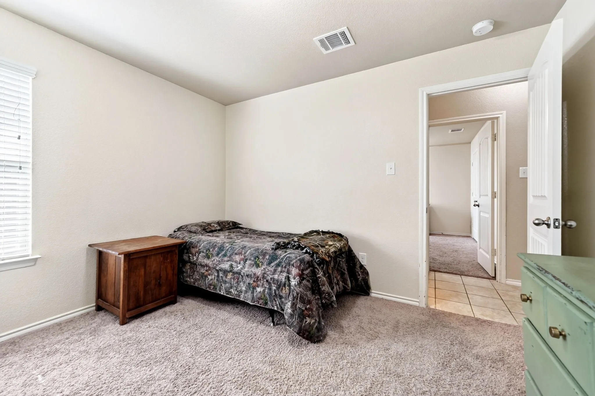 Soft beige wall tones, plush gray carpeting, white trim work, window with white blinds, and a white interior door