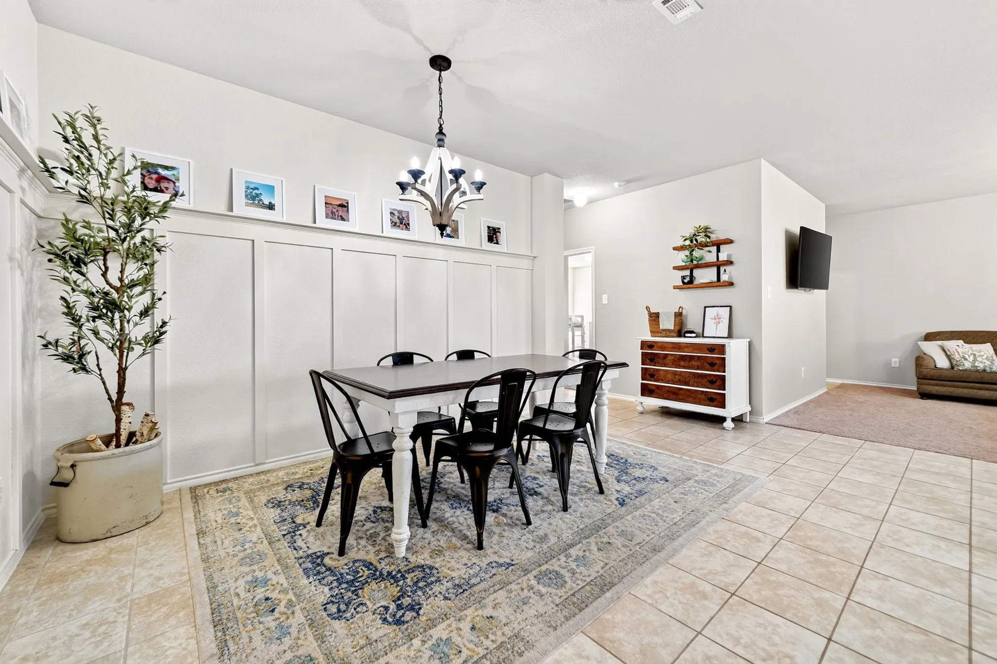 Dining area with board and batten accent wall, tile flooring, and a chandelier