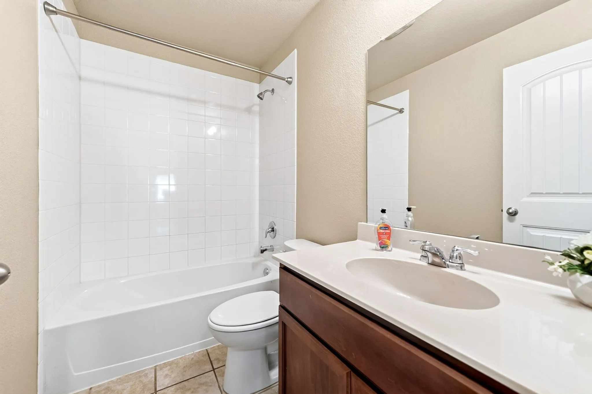 White tiled tub and shower combination with chrome fixtures
