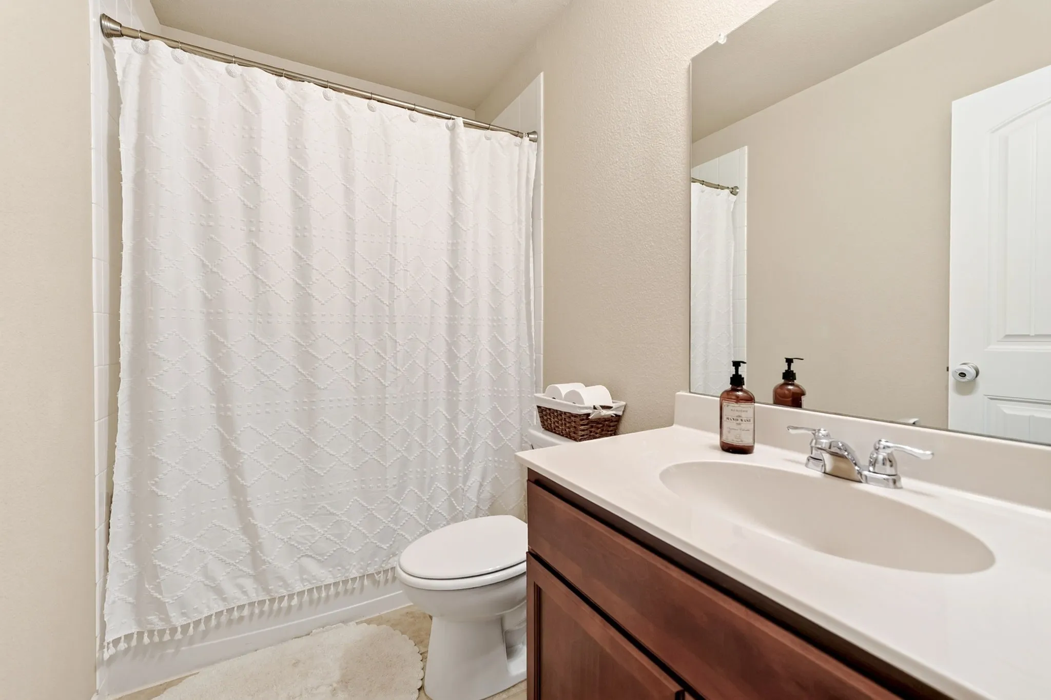 Bathroom featuring a shower/tub combination, single vanity with a solid surface countertop, and wood-finish cabinetry