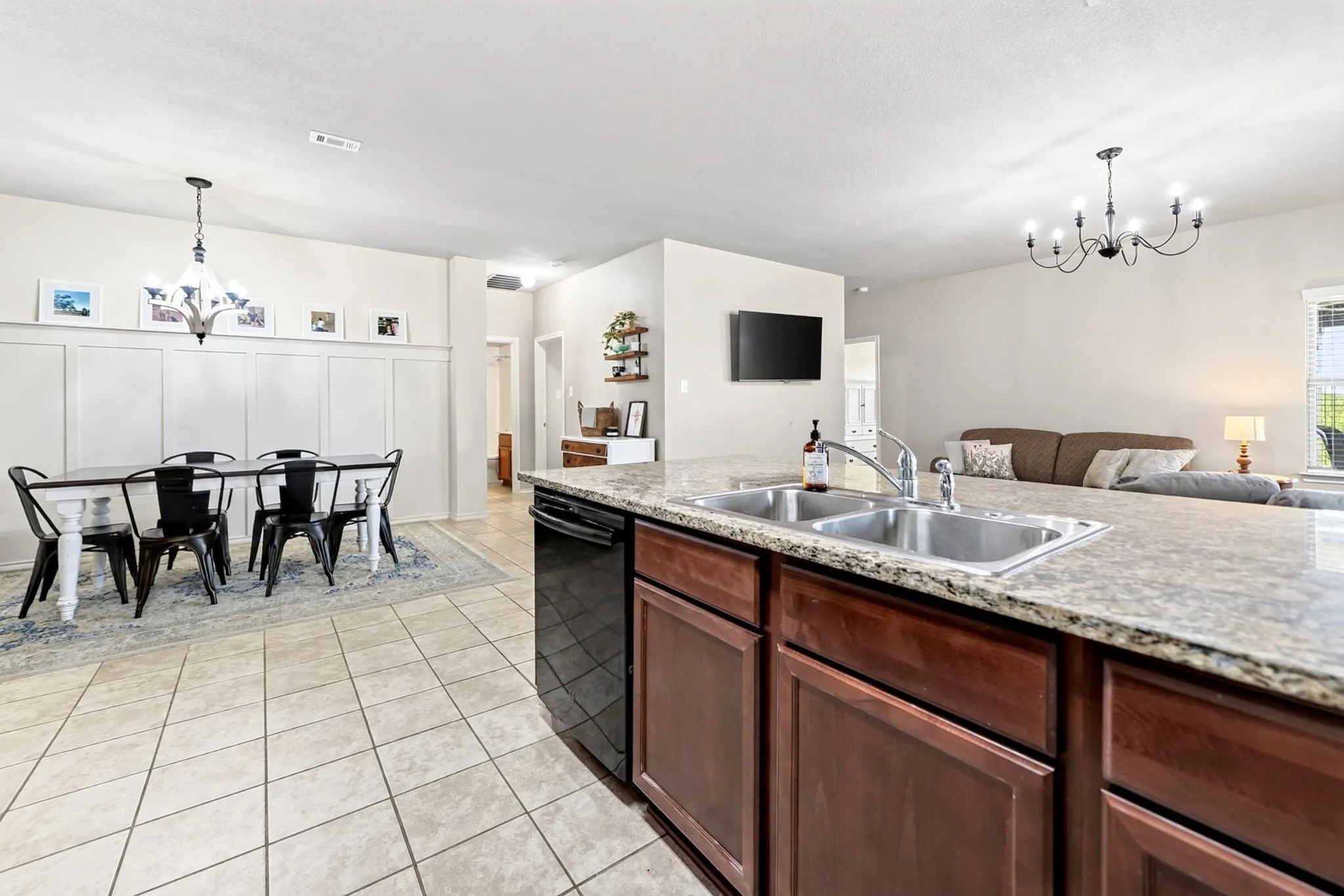 Kitchen island with a double basin stainless steel sink, granite-style countertop, and wood-finish cabinetry