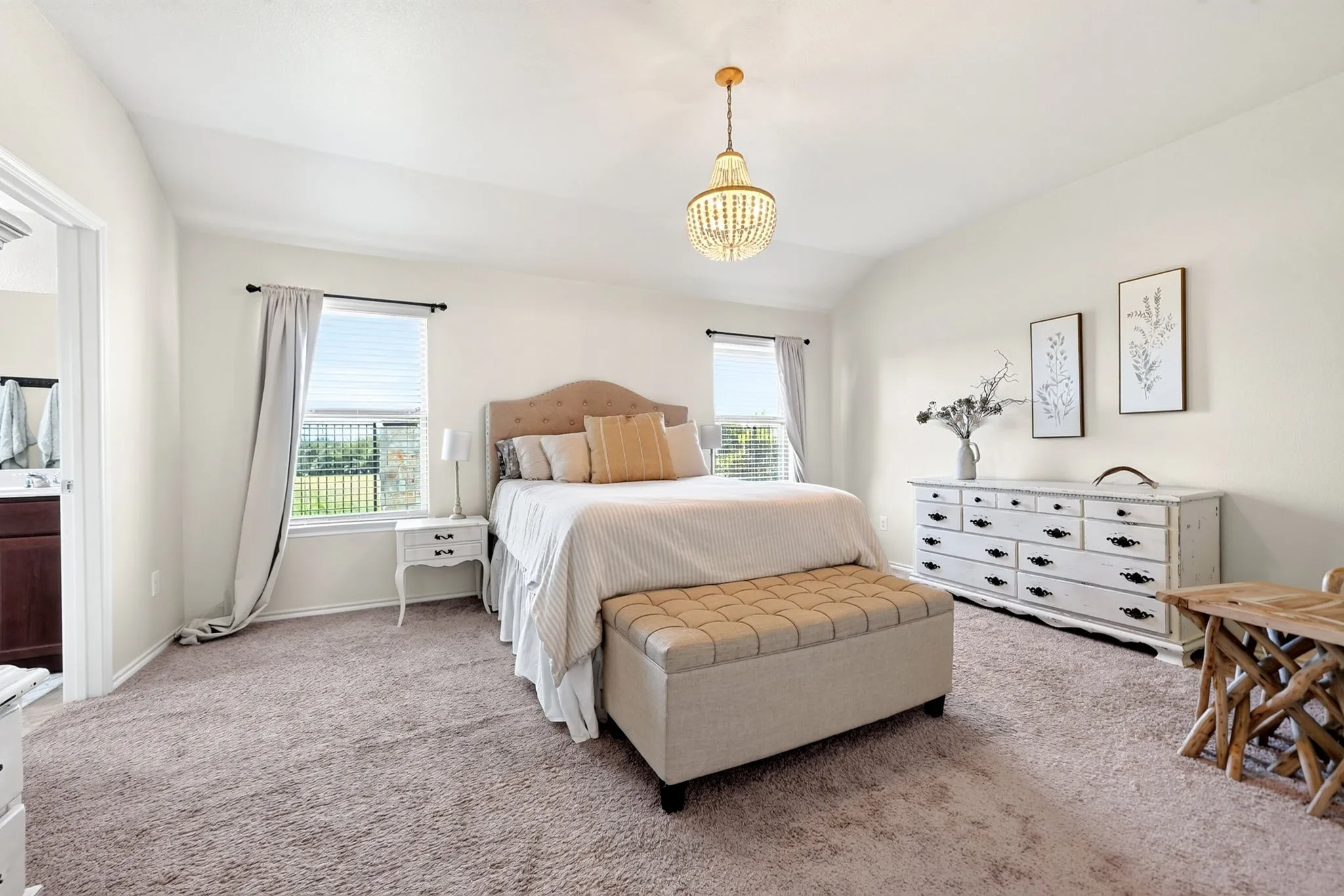 Vaulted ceiling with an ornate chandelier, carpeted flooring, and a large window with blinds