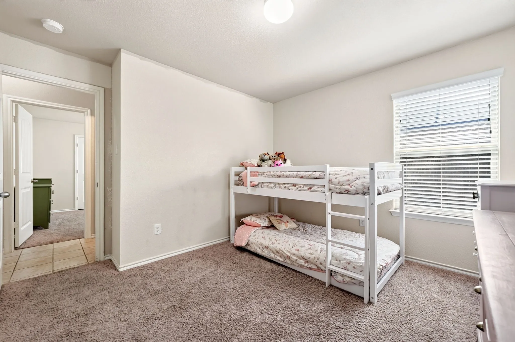 Carpeted flooring, neutral wall tones, window with horizontal blinds, flush mount ceiling lighting, and a white interior door