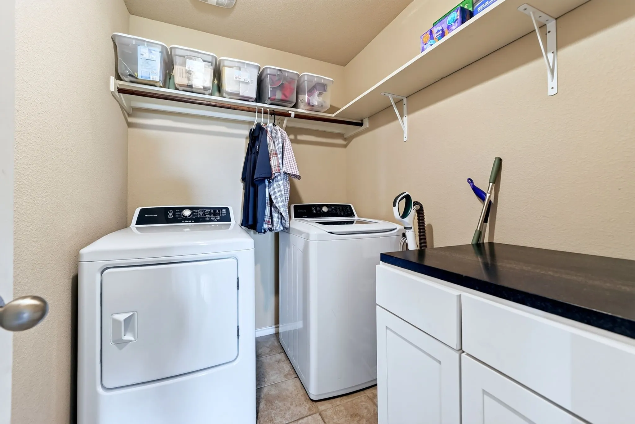 Tile flooring, wall-mounted shelving, built-in cabinetry, and a black countertop