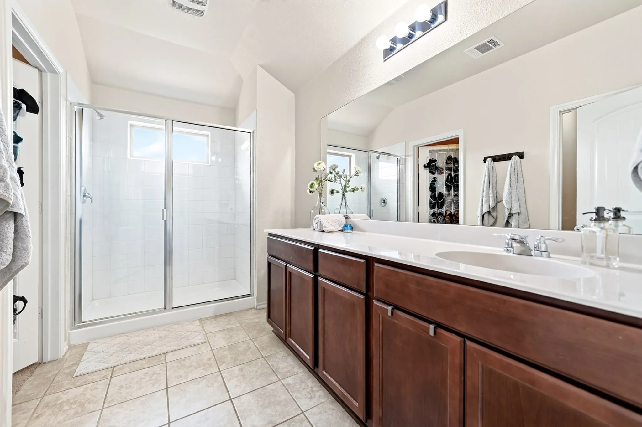 Double vanity with integrated sinks, white countertop, dark wood-finish cabinetry, and a large wall-mounted mirror