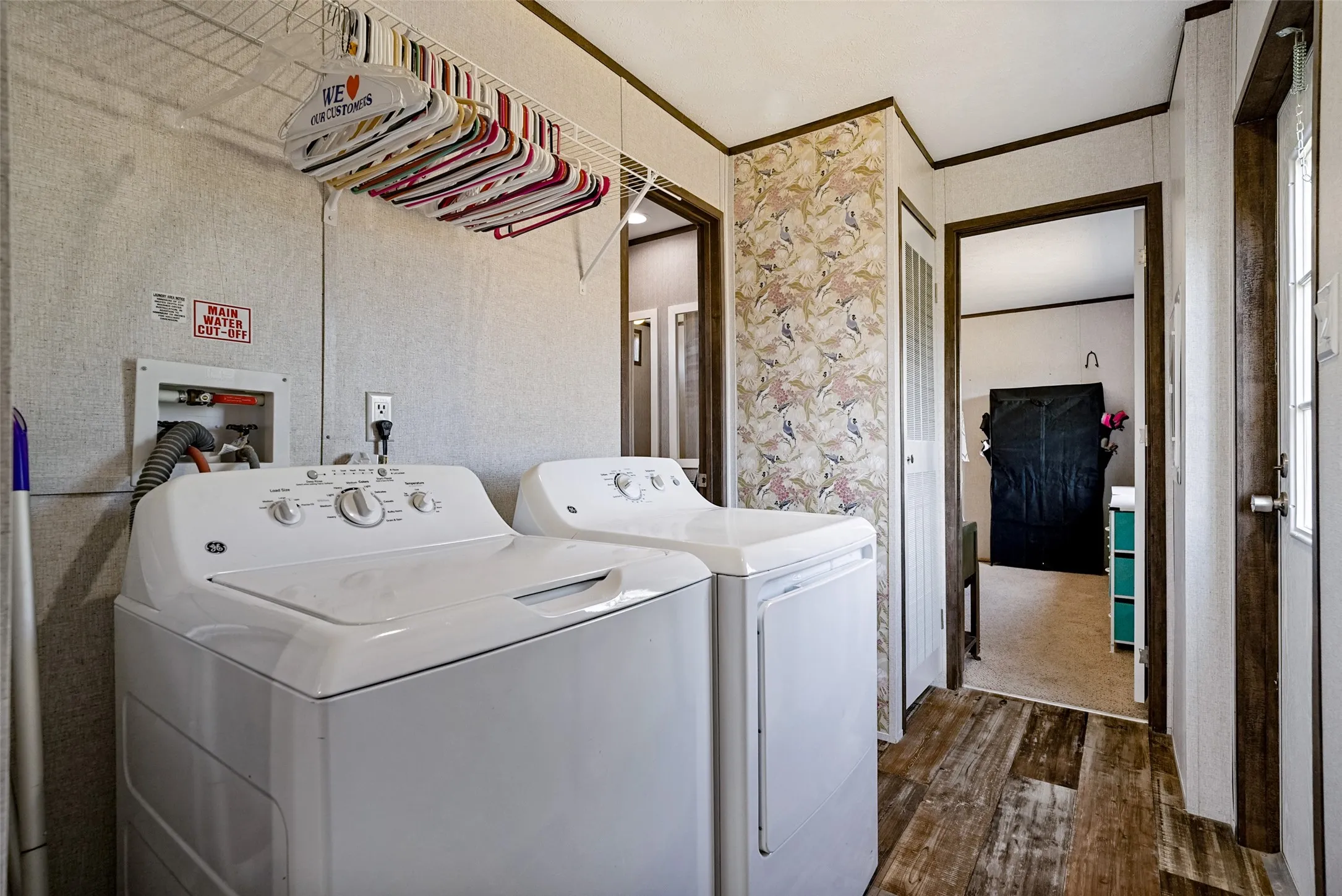 Dedicated laundry area featuring wood-finish flooring, included appliances, and a wire rack storage solution