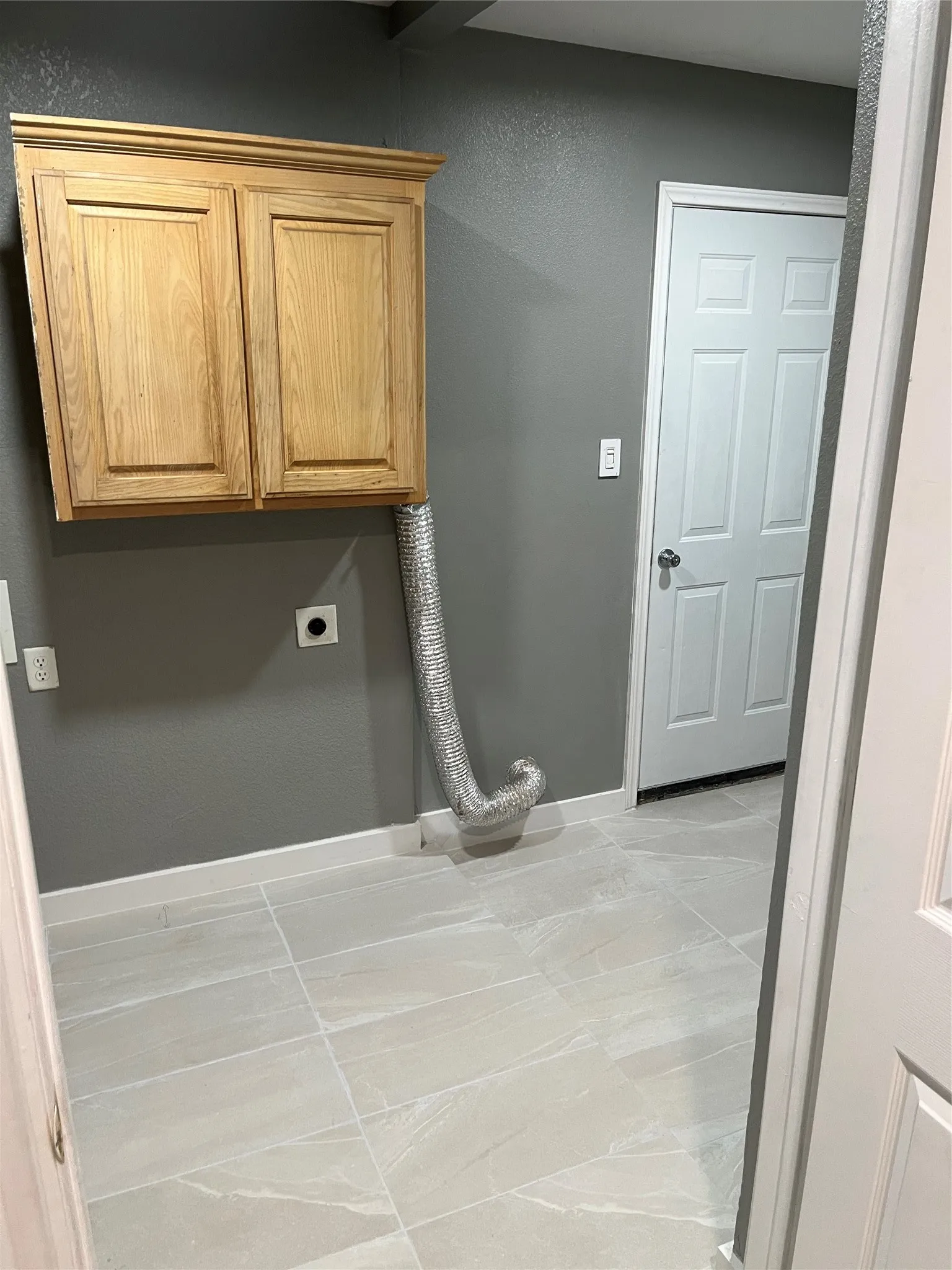 Laundry room featuring light tile flooring, electric dryer hookup, and cabinets