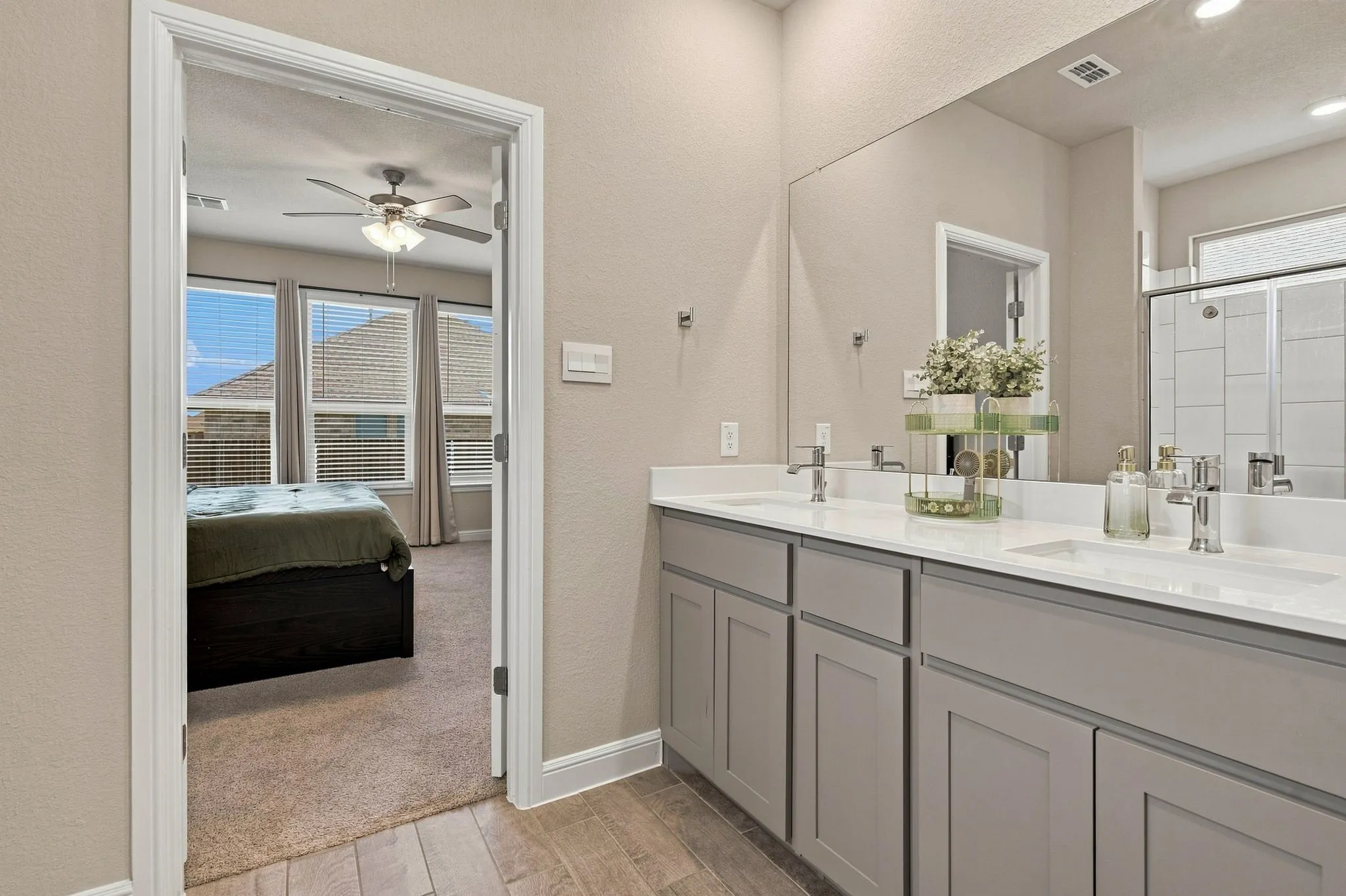 Double vanity with undermount sinks, gray shaker-style cabinetry, and wood-finish flooring