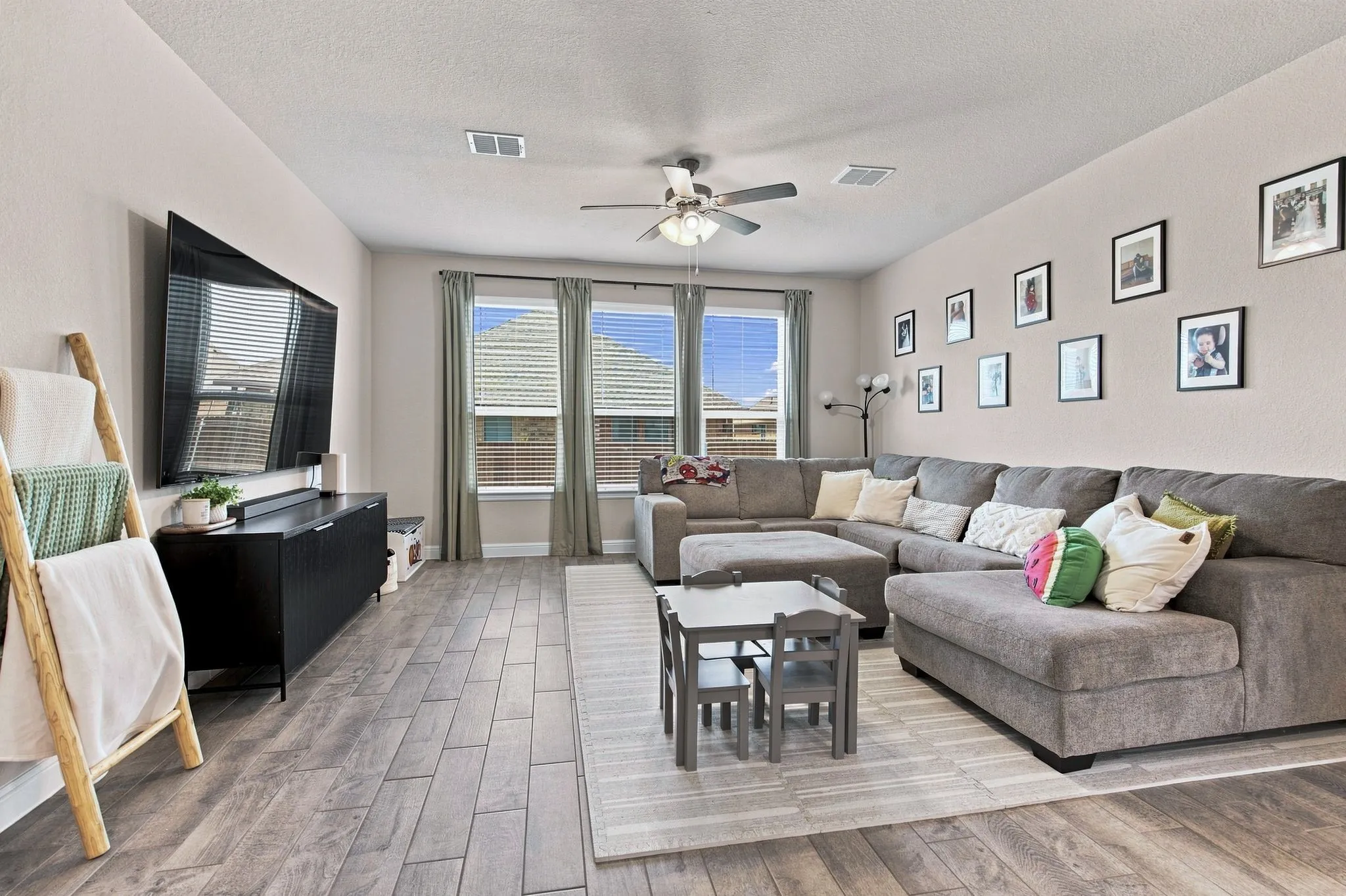 Wood-finish flooring throughout, multiple windows, and a ceiling fan with integrated lighting