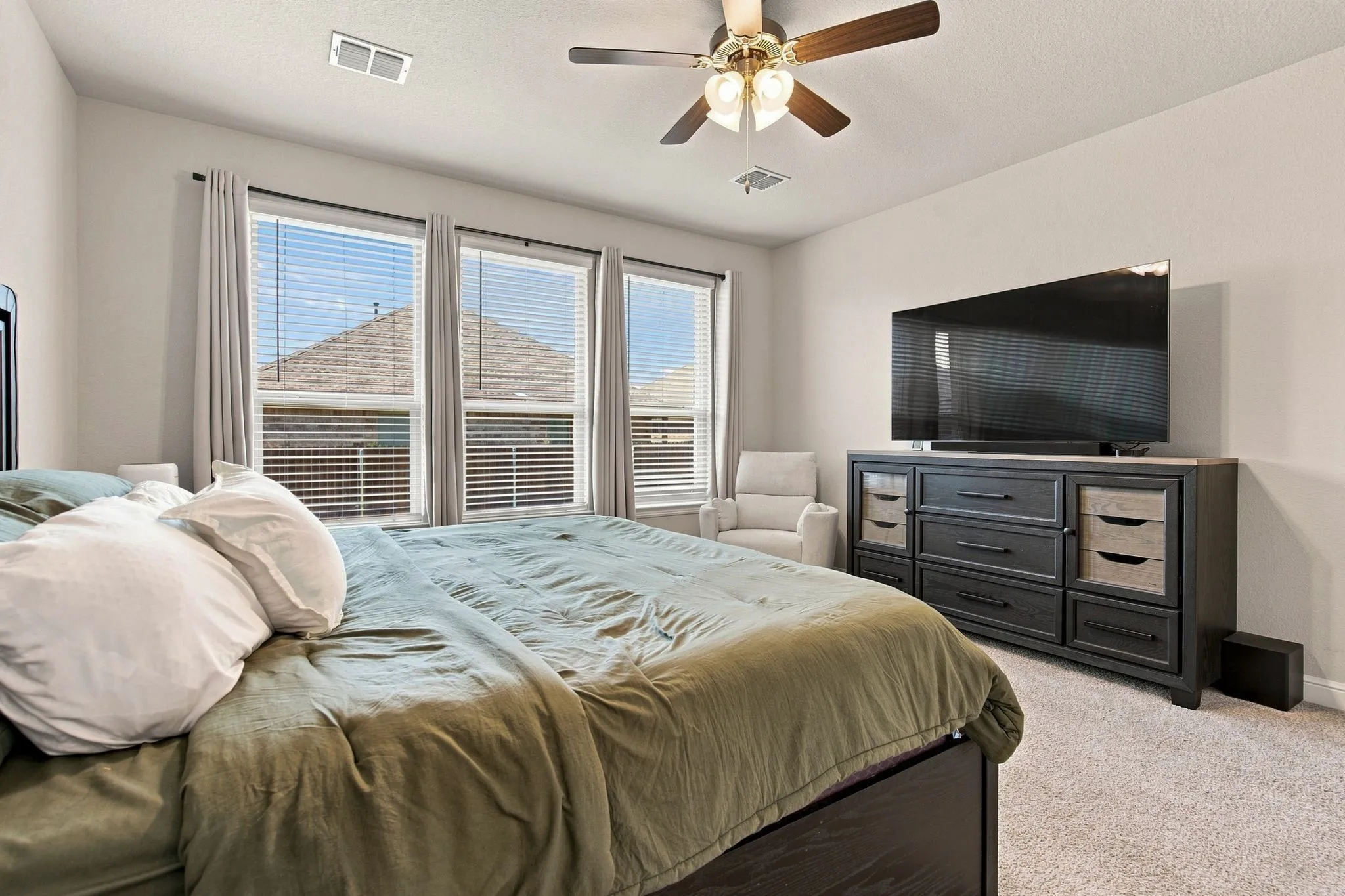 Triple window ensemble with blinds and curtain rods, ceiling fan with integrated lighting, and neutral carpeting