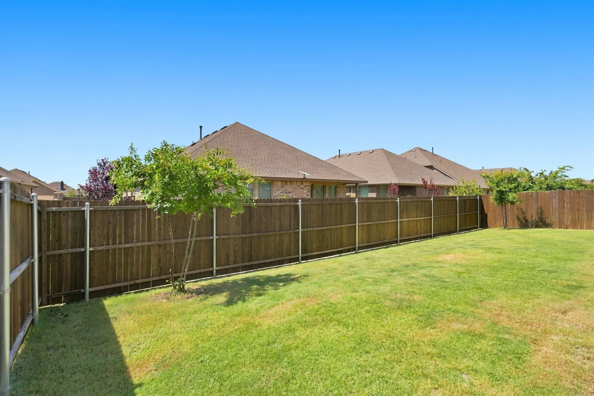Expansive backyard featuring a manicured lawn, established landscaping, and privacy fencing