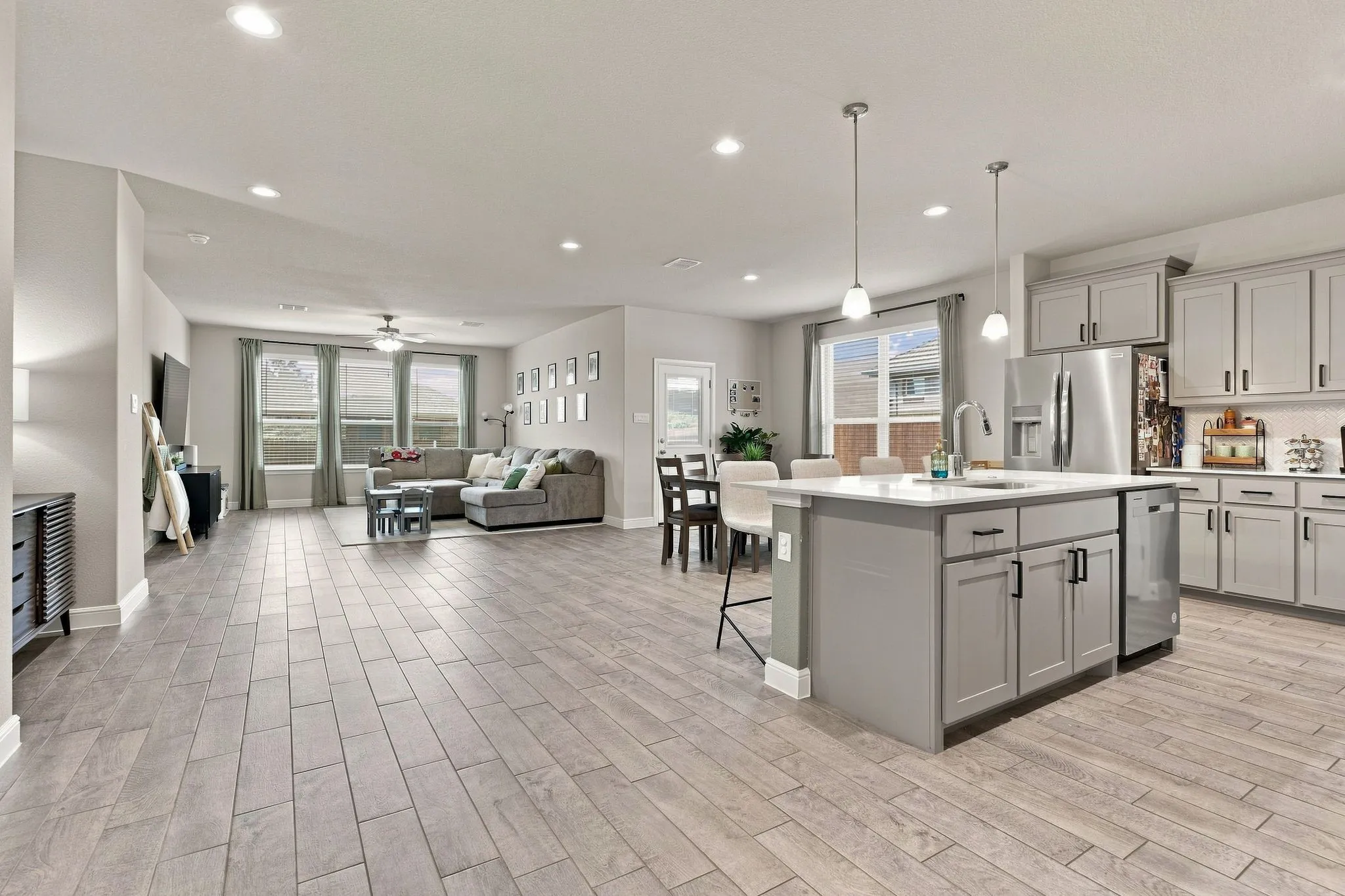 Open-concept living space featuring wood-finish flooring, recessed lighting, a ceiling fan, and large windows with blinds