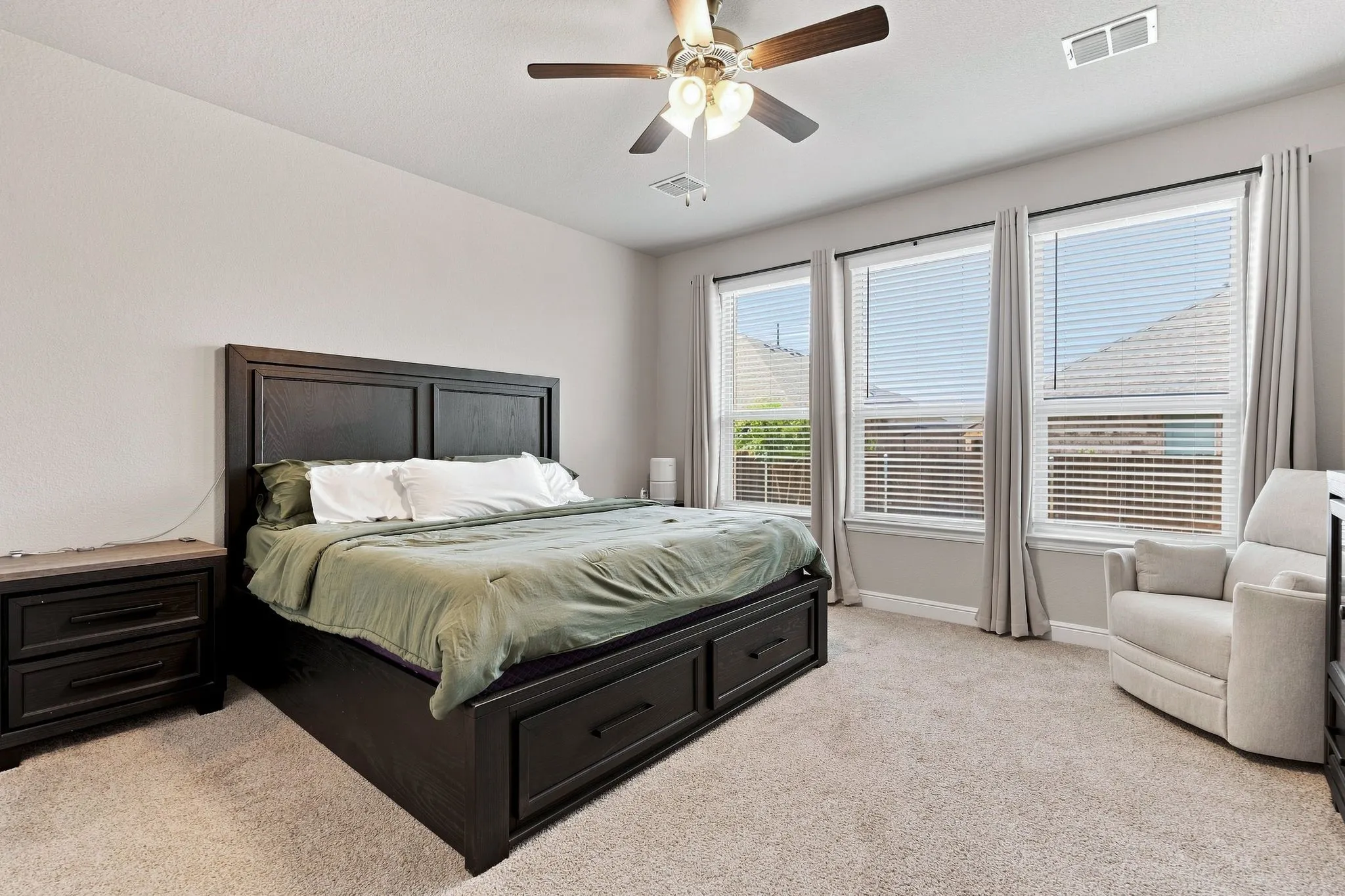 Light-toned walls, recessed ceiling fan with integrated lighting, three large windows with blinds, and neutral-toned carpeting