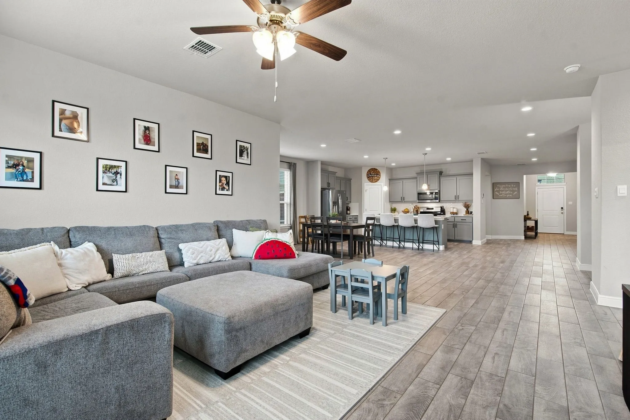Open-concept living space with wood-finish flooring, recessed lighting, and a ceiling fan