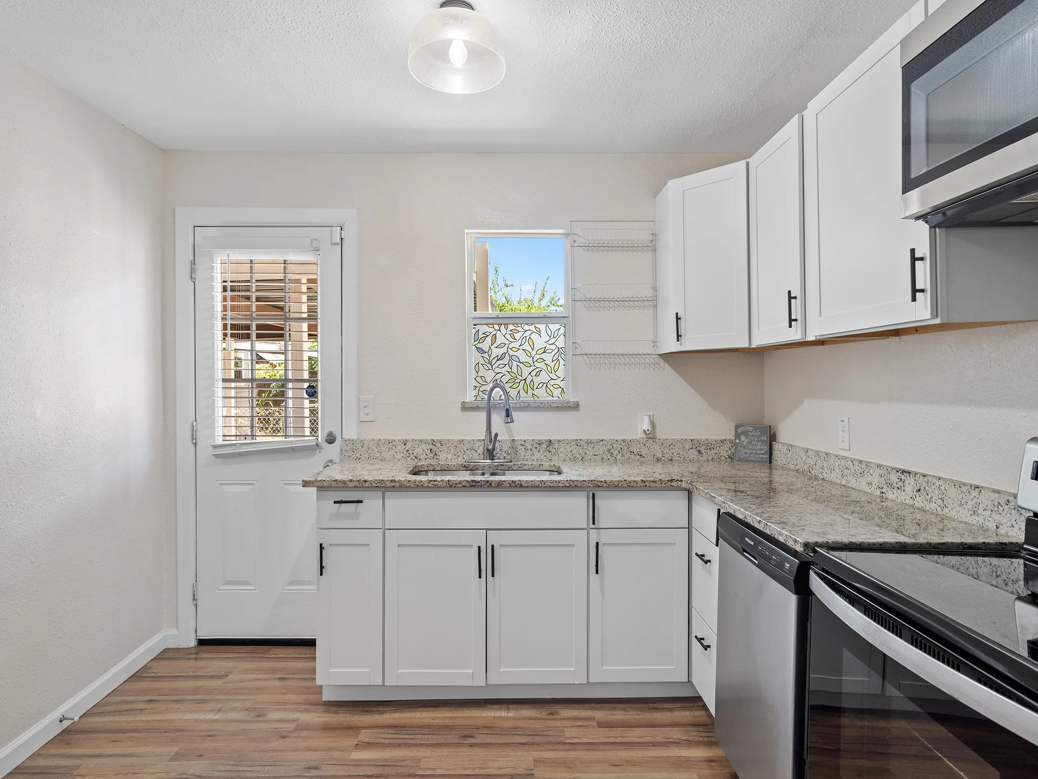 Clean, functional kitchen workspace featuring granite counters, ample cabinetry, and a window over the sink.