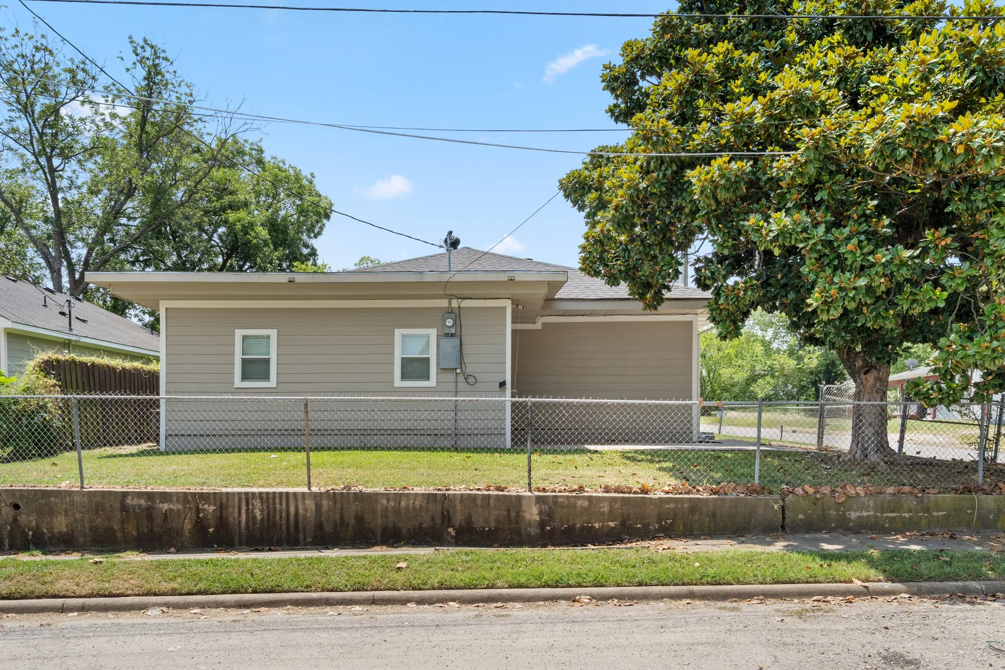 Corner-lot setting with a mature magnolia tree creates beautiful shade and the feel of an additional side yard, adding both character and usable outdoor space.