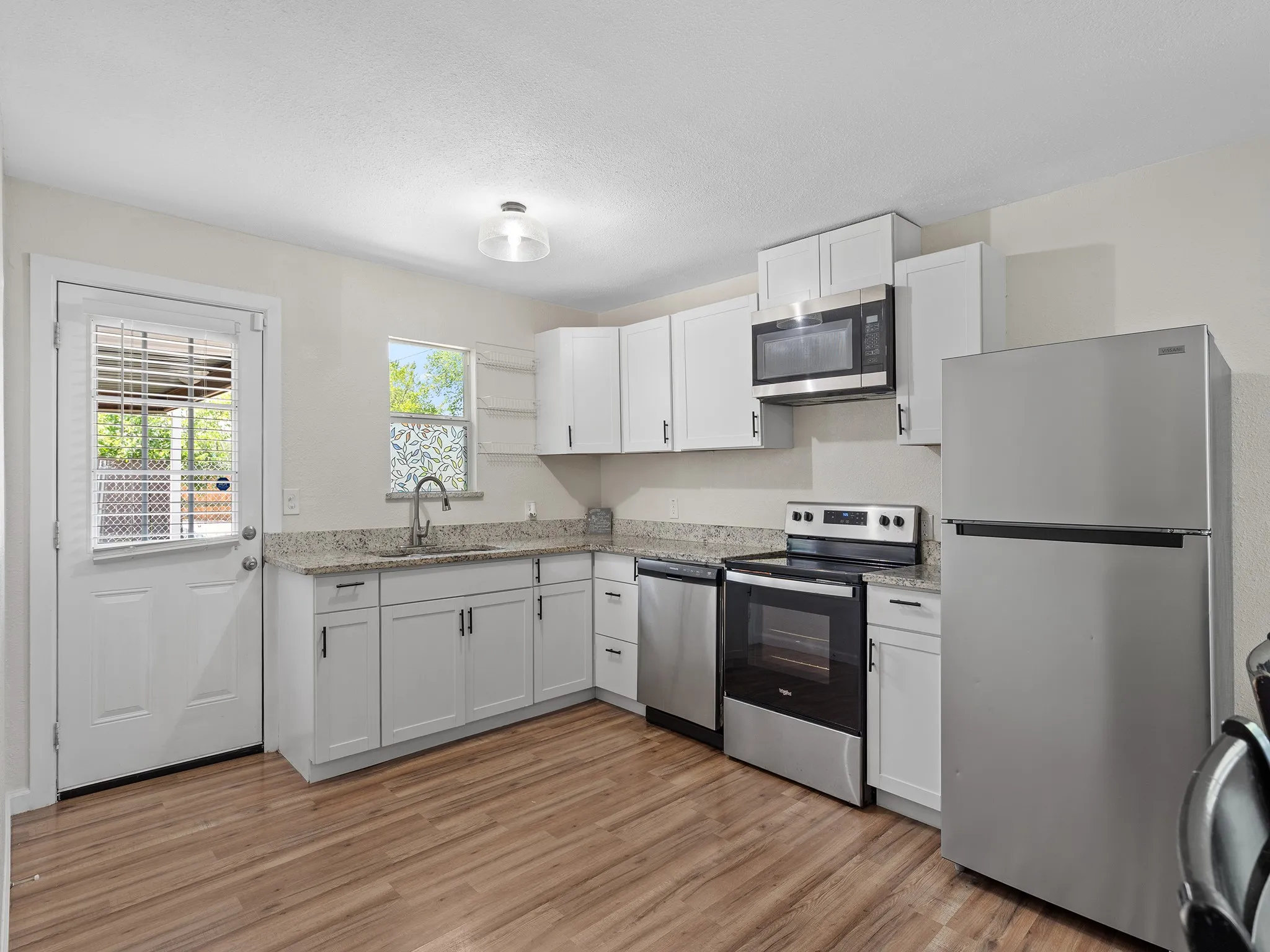 Updated kitchen with white shaker-style cabinetry and convenient access to the covered outdoor area.