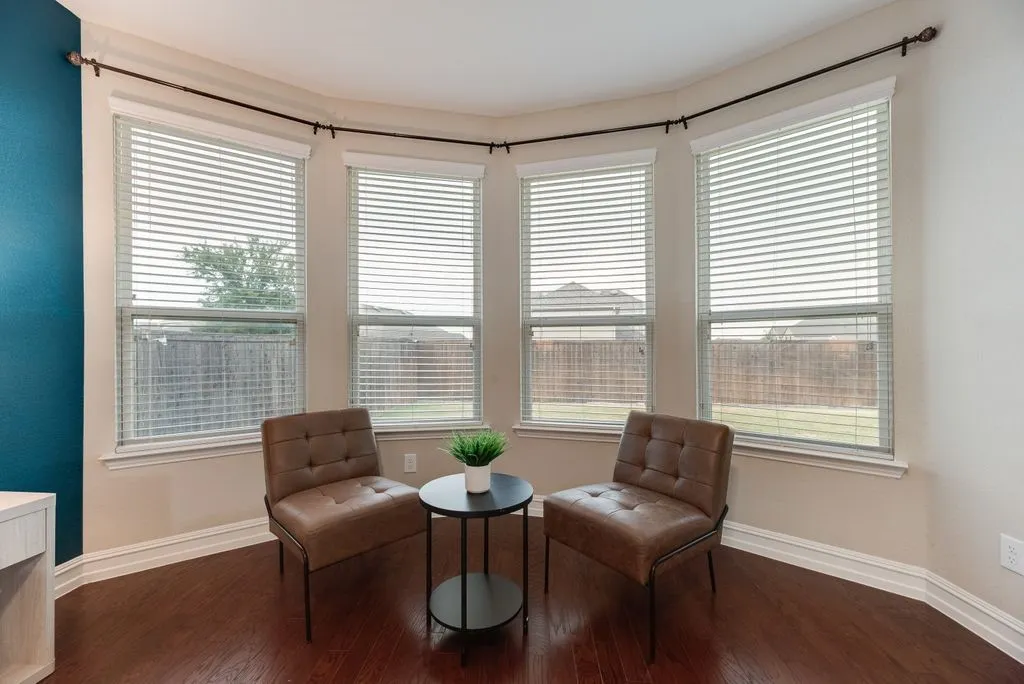 Bay window with multiple large windows, wood-finish flooring, and a contrasting accent wall