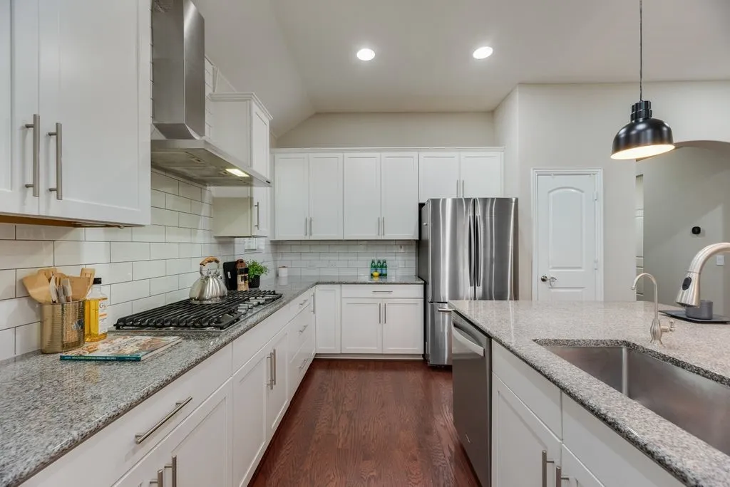 Kitchen featuring white shaker cabinetry, stainless steel appliances, granite countertops, subway tile backsplash, and dark wood-finish flooring