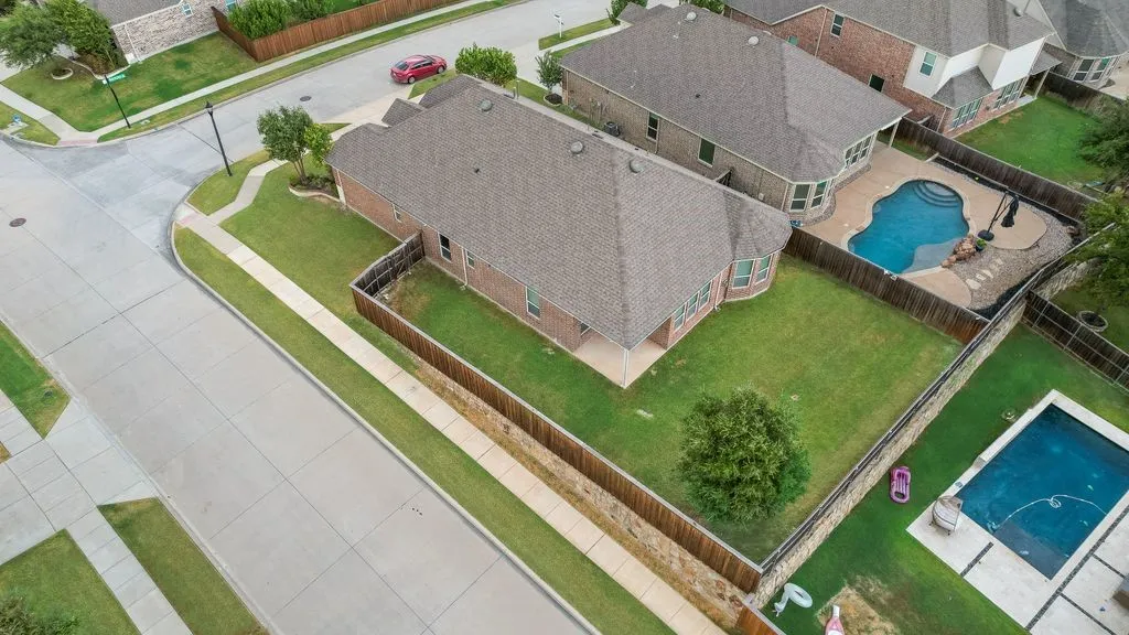 Expansive lot featuring a green lawn, established tree, and a paved street