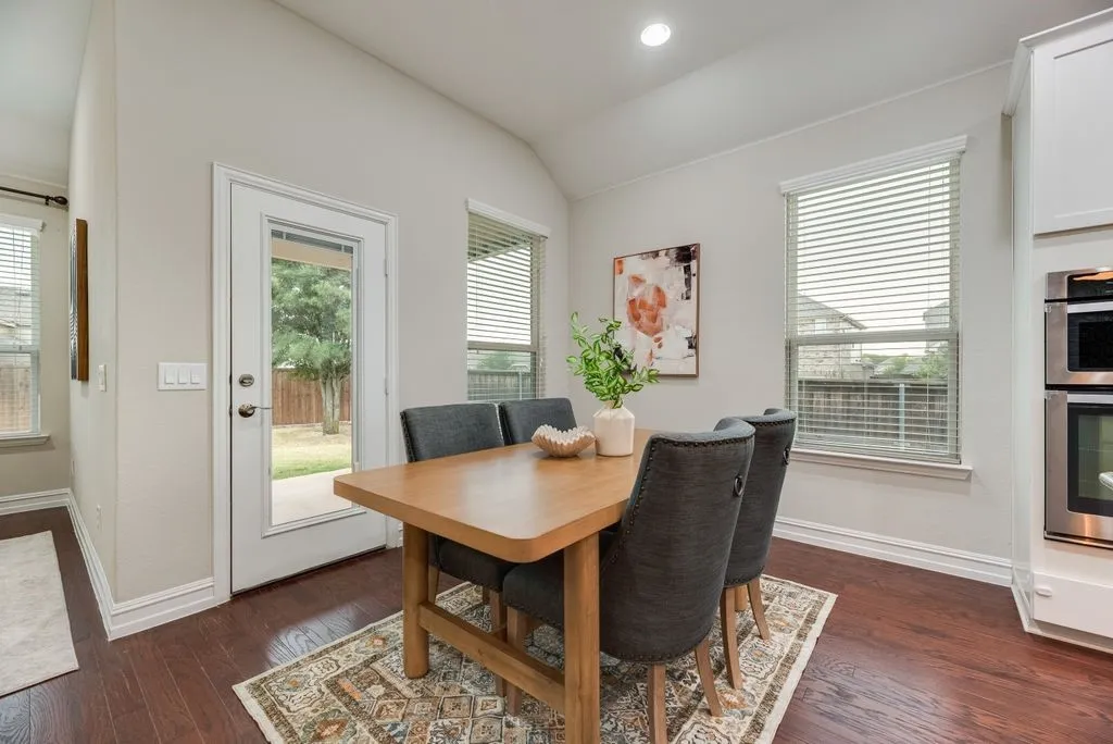 Vaulted ceiling with recessed lighting, wood-finish flooring, white trim, and a glass-paneled exterior door