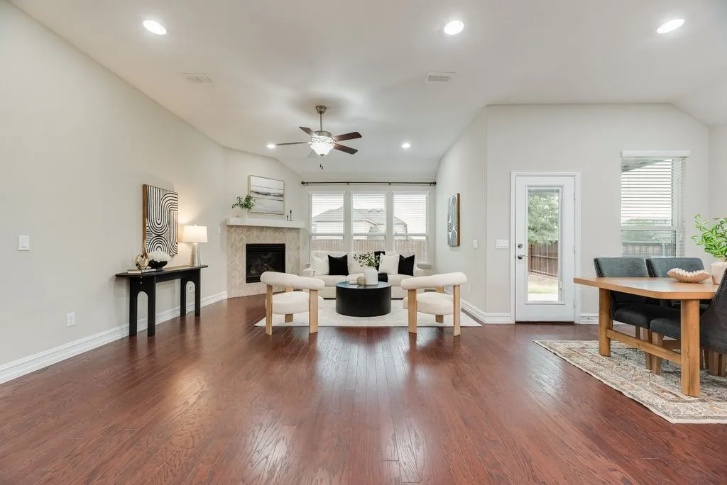 Wood-finish flooring throughout, vaulted ceilings with recessed lighting, and a corner fireplace with a tiled surround