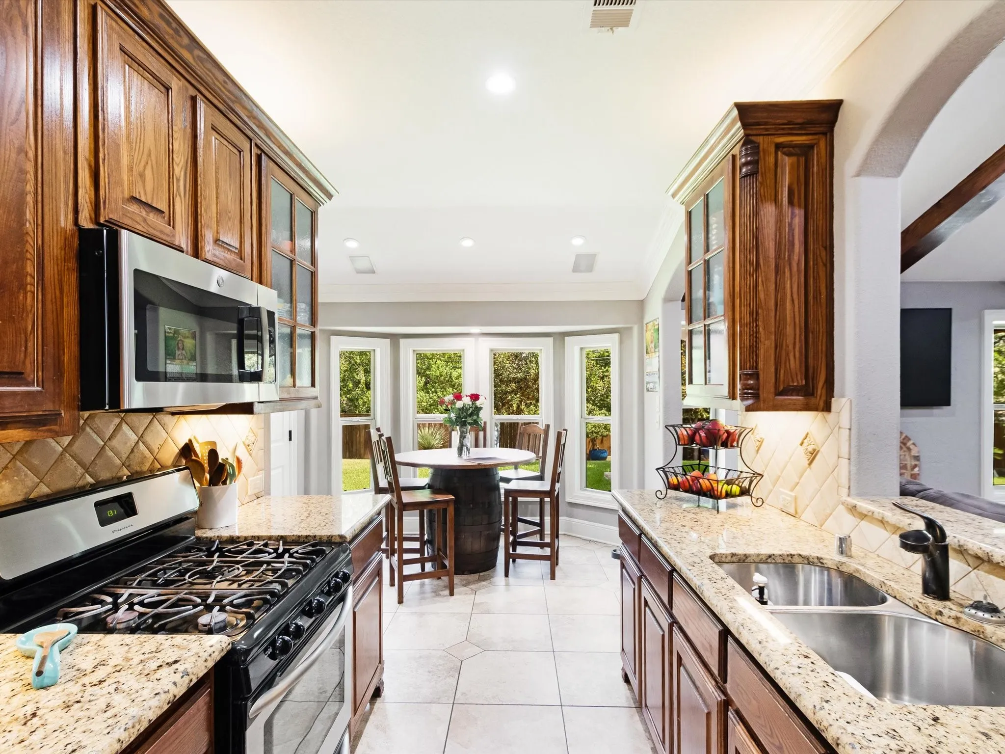 Kitchen featuring wood cabinetry, stainless steel appliances, granite countertops, and a tiled backsplash