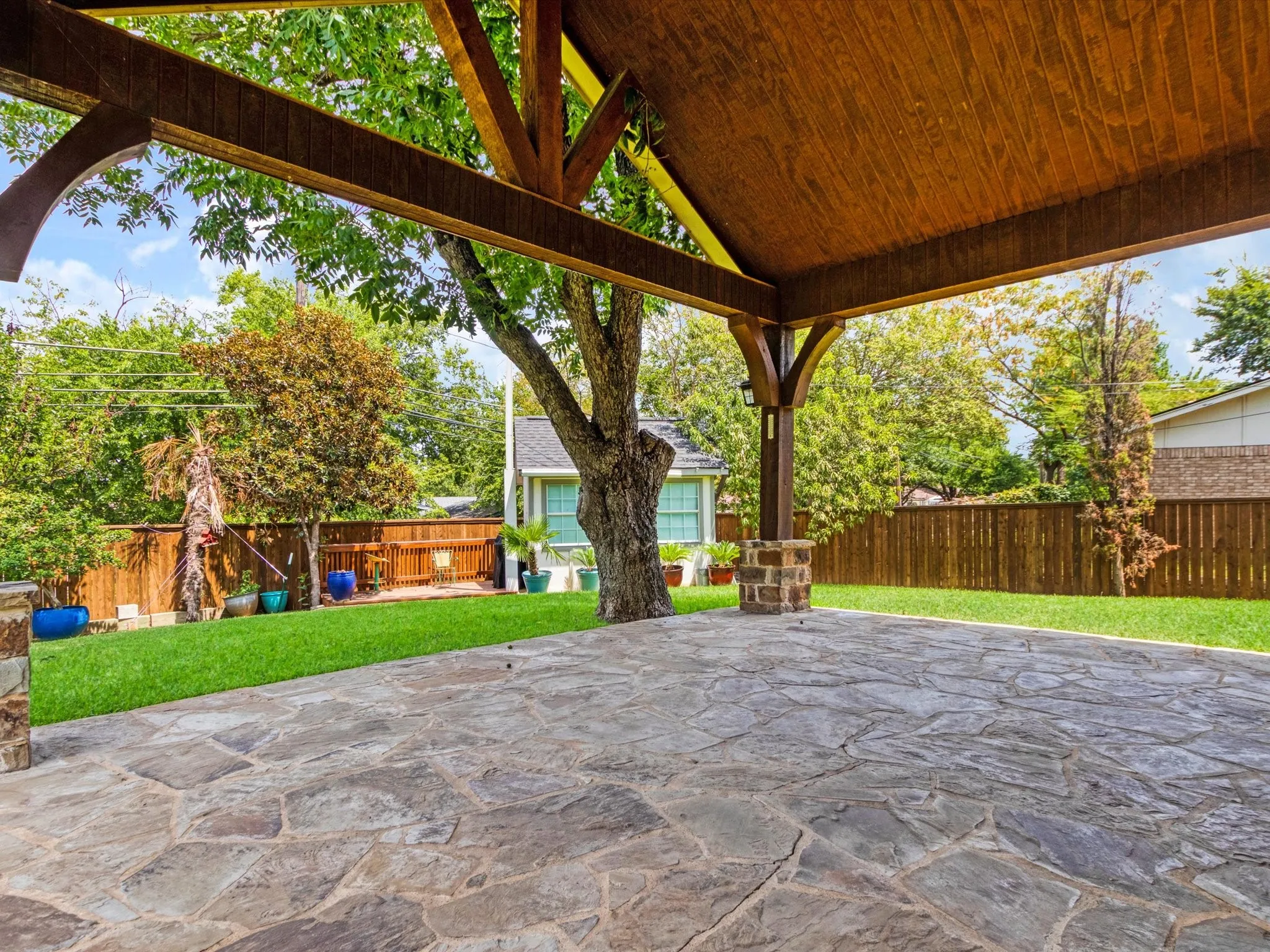Expansive outdoor patio with flagstone paving and a wood-beamed overhead structure