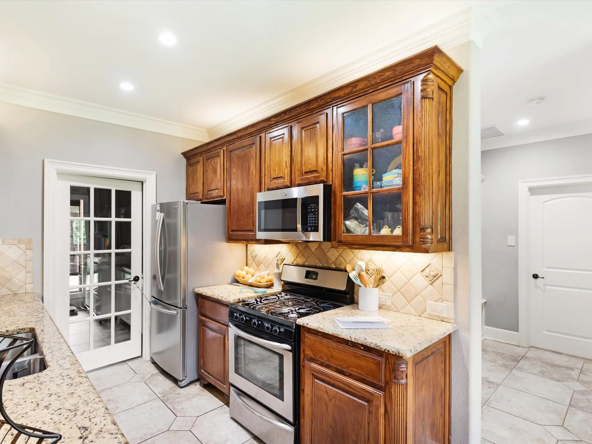Kitchen featuring wood cabinetry, stainless steel appliances, granite-style countertops, tile backsplash, and hexagonal tile flooring