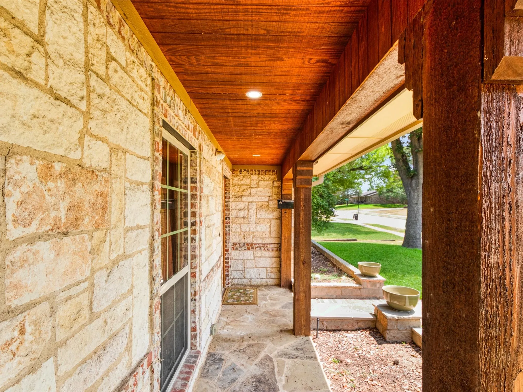 Stone and brick exterior with a wood-finish ceiling, flagstone walkway, and wood posts
