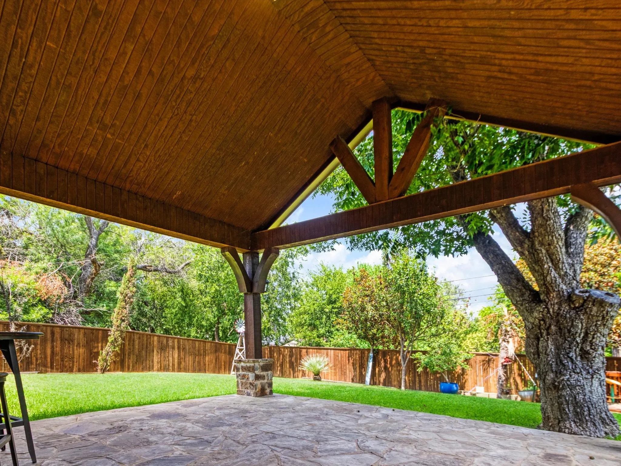 Covered patio with a wood-paneled ceiling, exposed wood beams, and a flagstone surface
