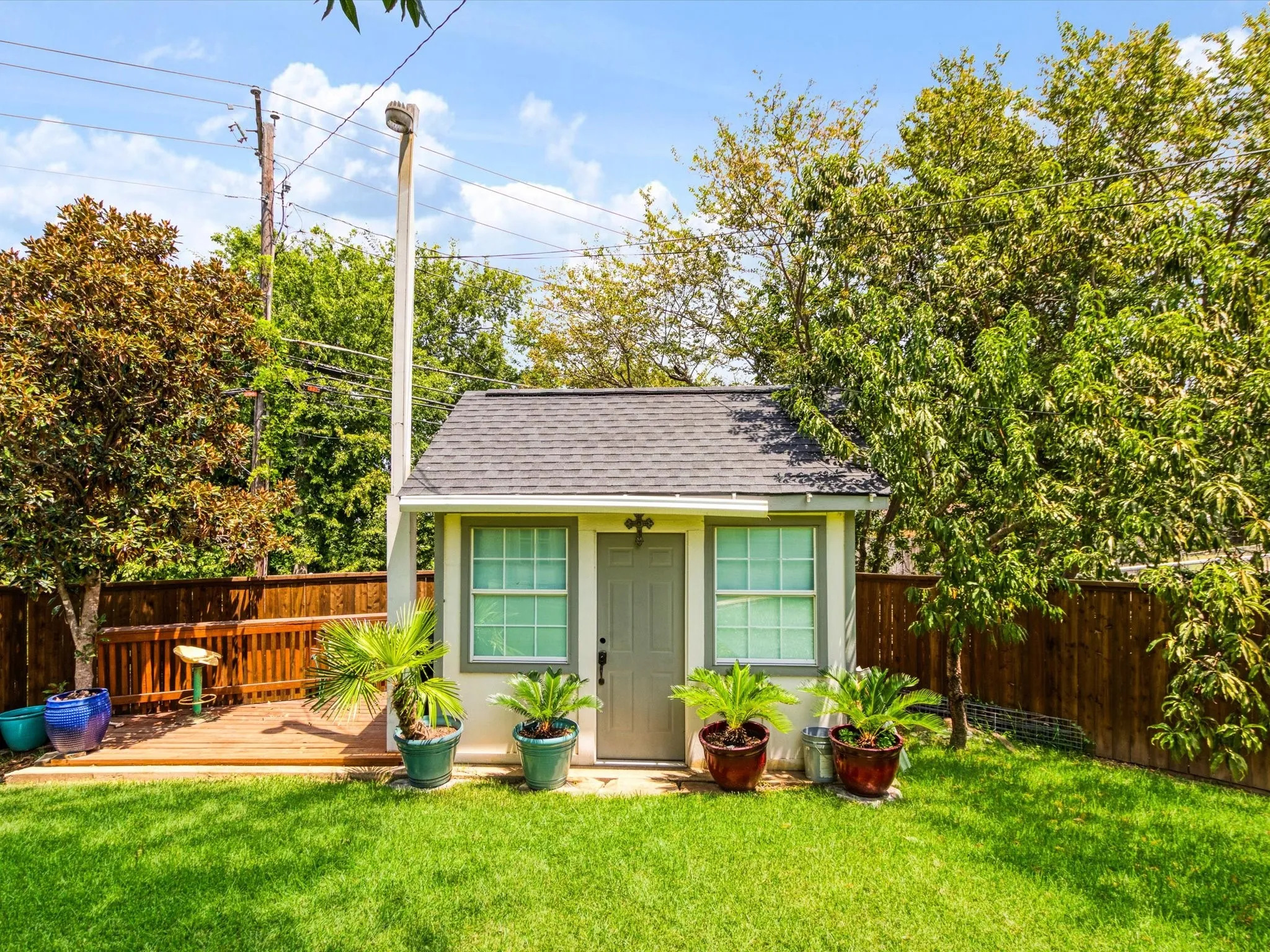 Manicured lawn with a detached auxiliary structure featuring a shingled roof, a window, and a door