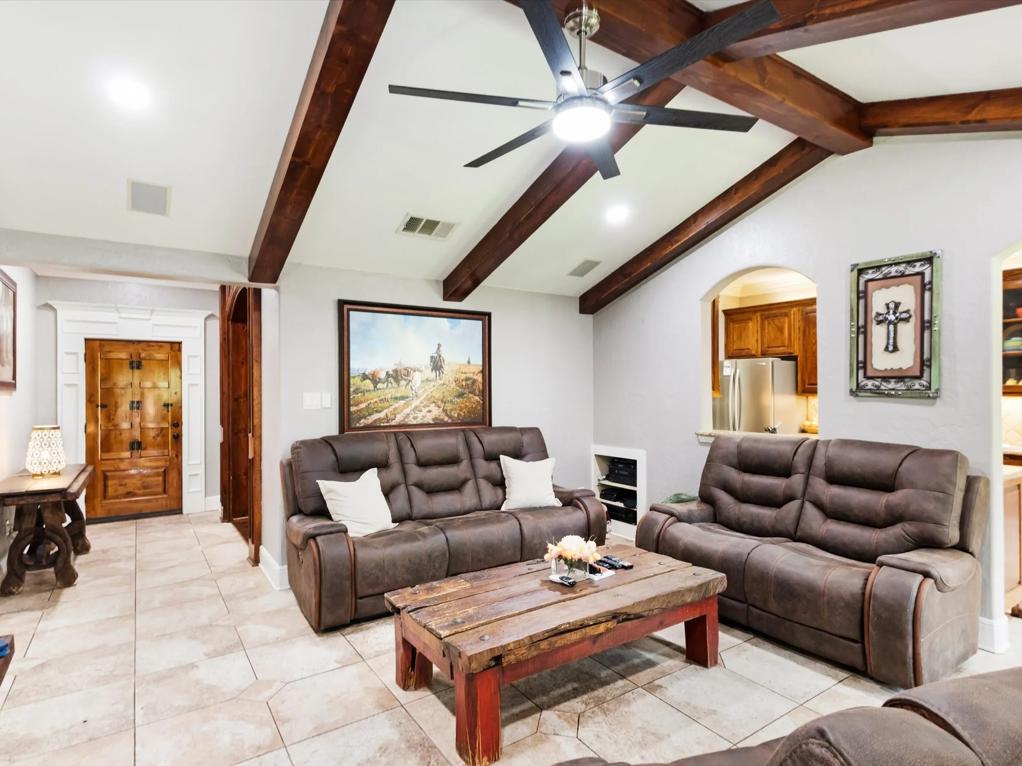 Vaulted ceiling with exposed wood beams, tile flooring, recessed lighting, and a decorative wood-paneled door