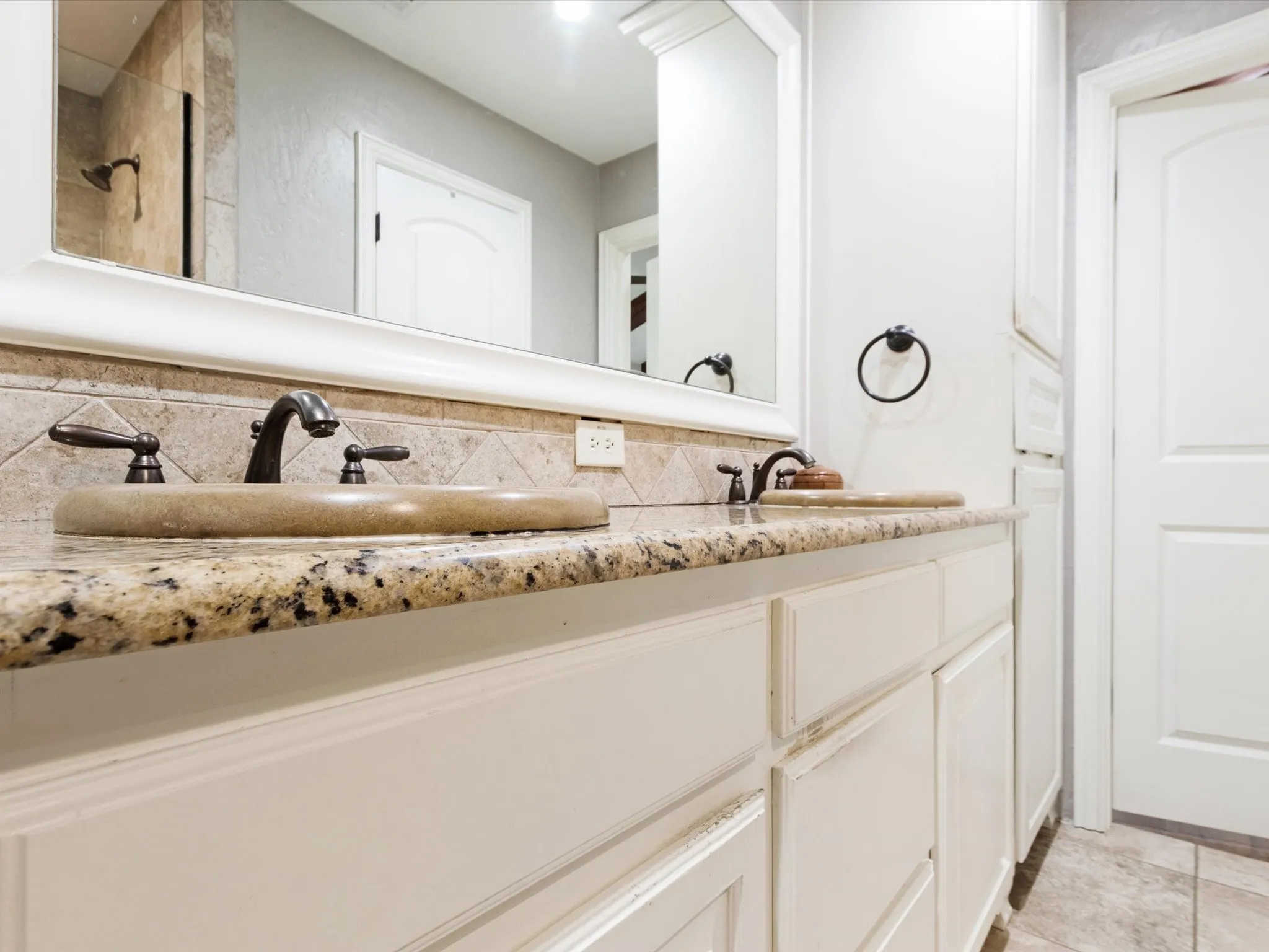 Dual vanity with granite countertops, stone vessel sinks, and bronze-finish fixtures