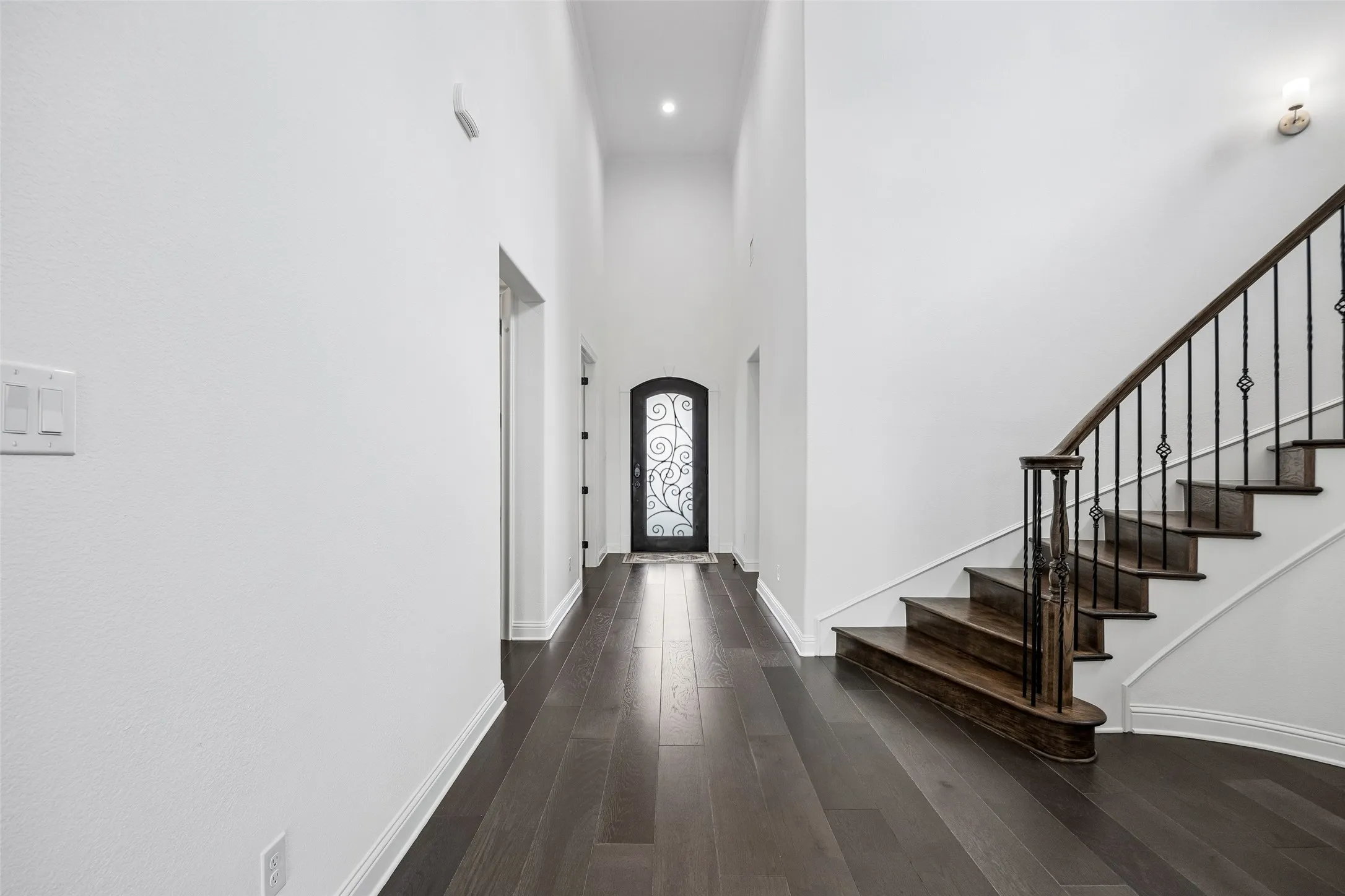 Wood-finish flooring throughout, an arched entryway, and a custom wrought iron front door