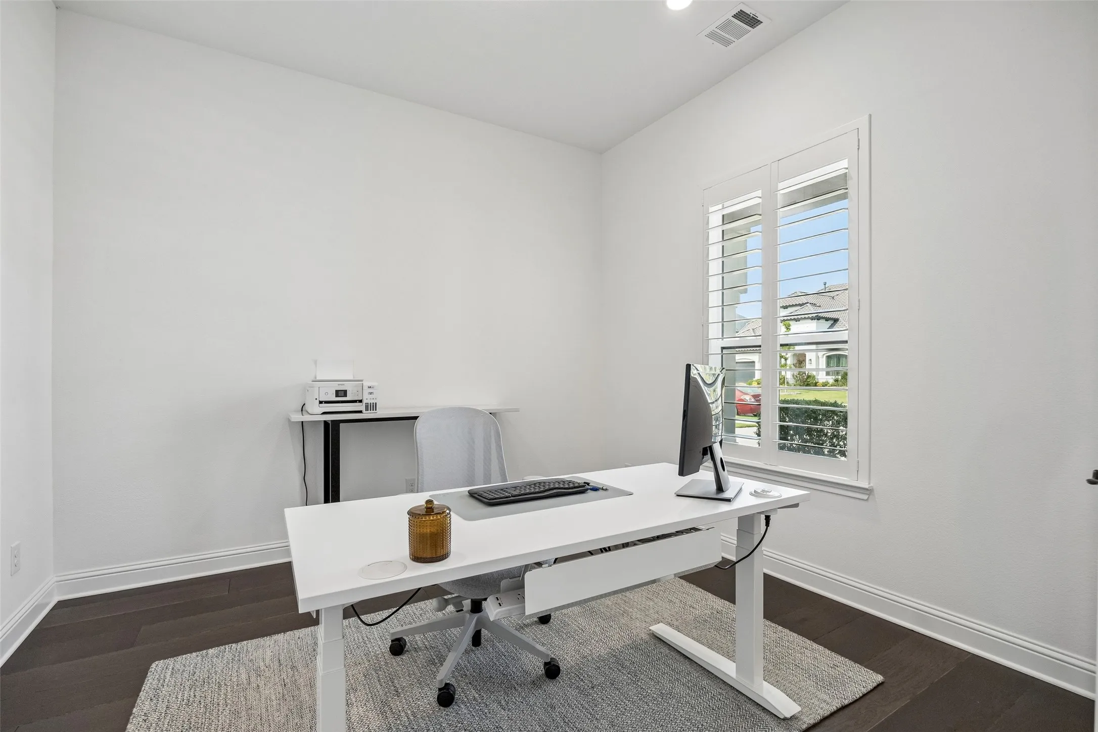 Recessed lighting, dark wood-finish flooring, white plantation shutters, and white wall finishes