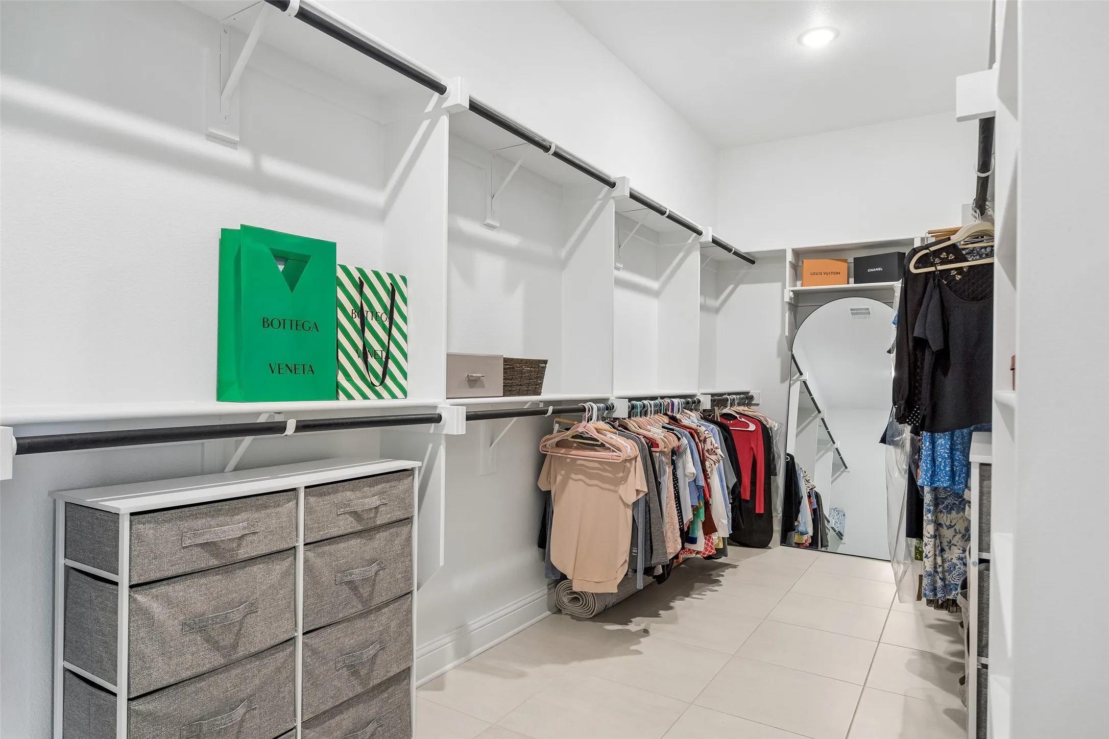 Built-in shelving with hanging rods, recessed lighting, and light-toned tile flooring
