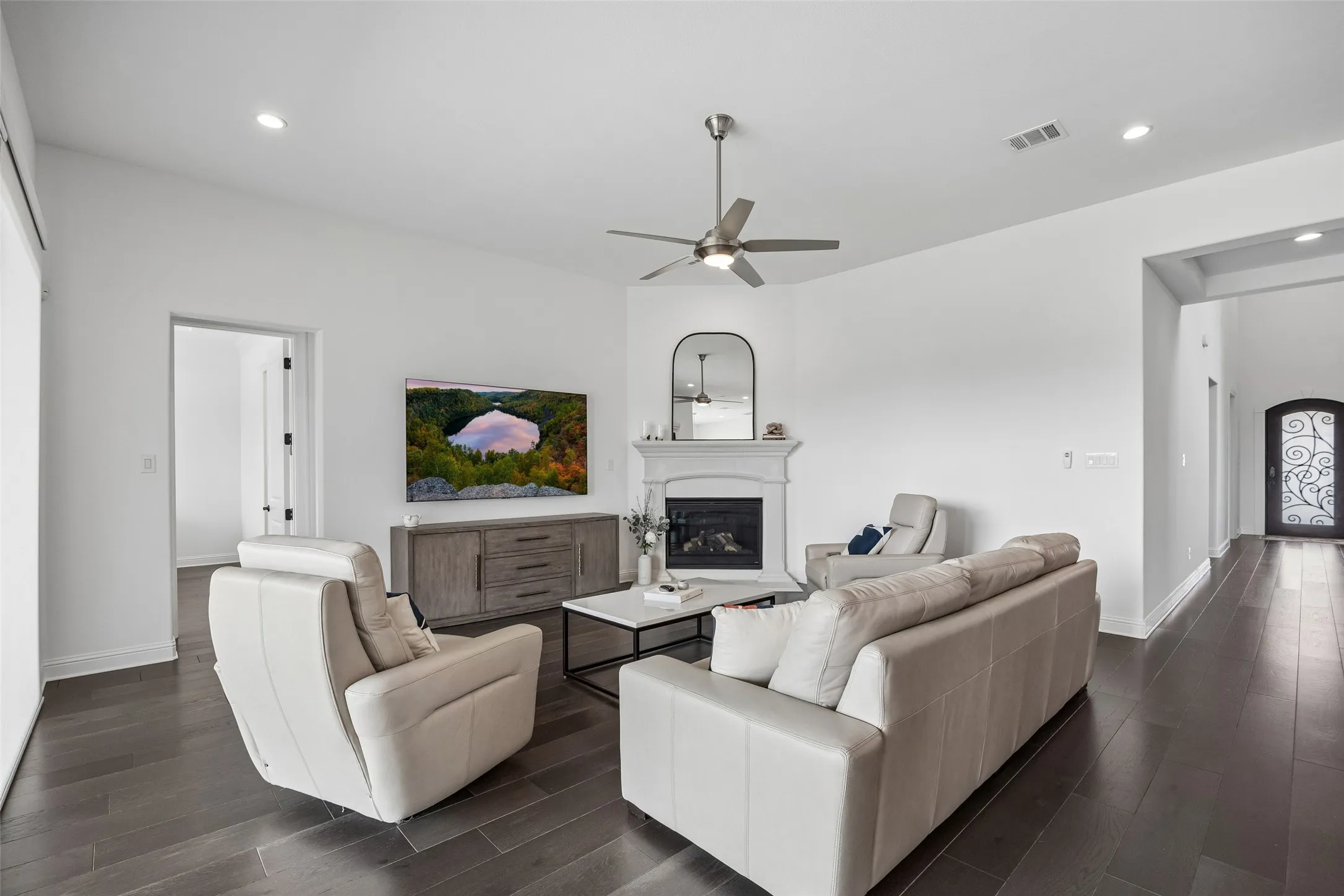 Spacious living area featuring wood-finish flooring, a fireplace with a mantel, recessed lighting, and a ceiling fan