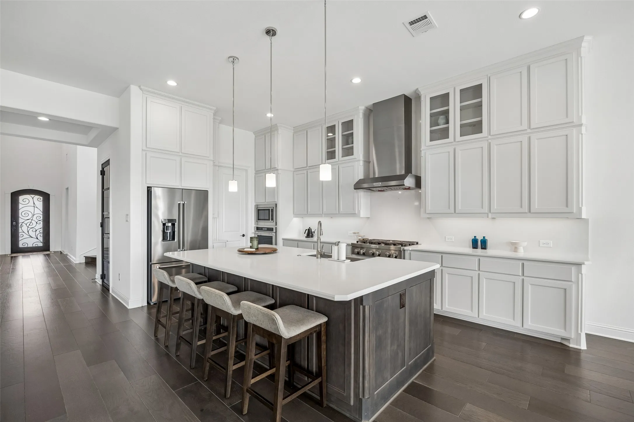 Gourmet kitchen with a large center island, stainless steel appliances, extensive cabinetry, light countertops, and dark wood-finish flooring