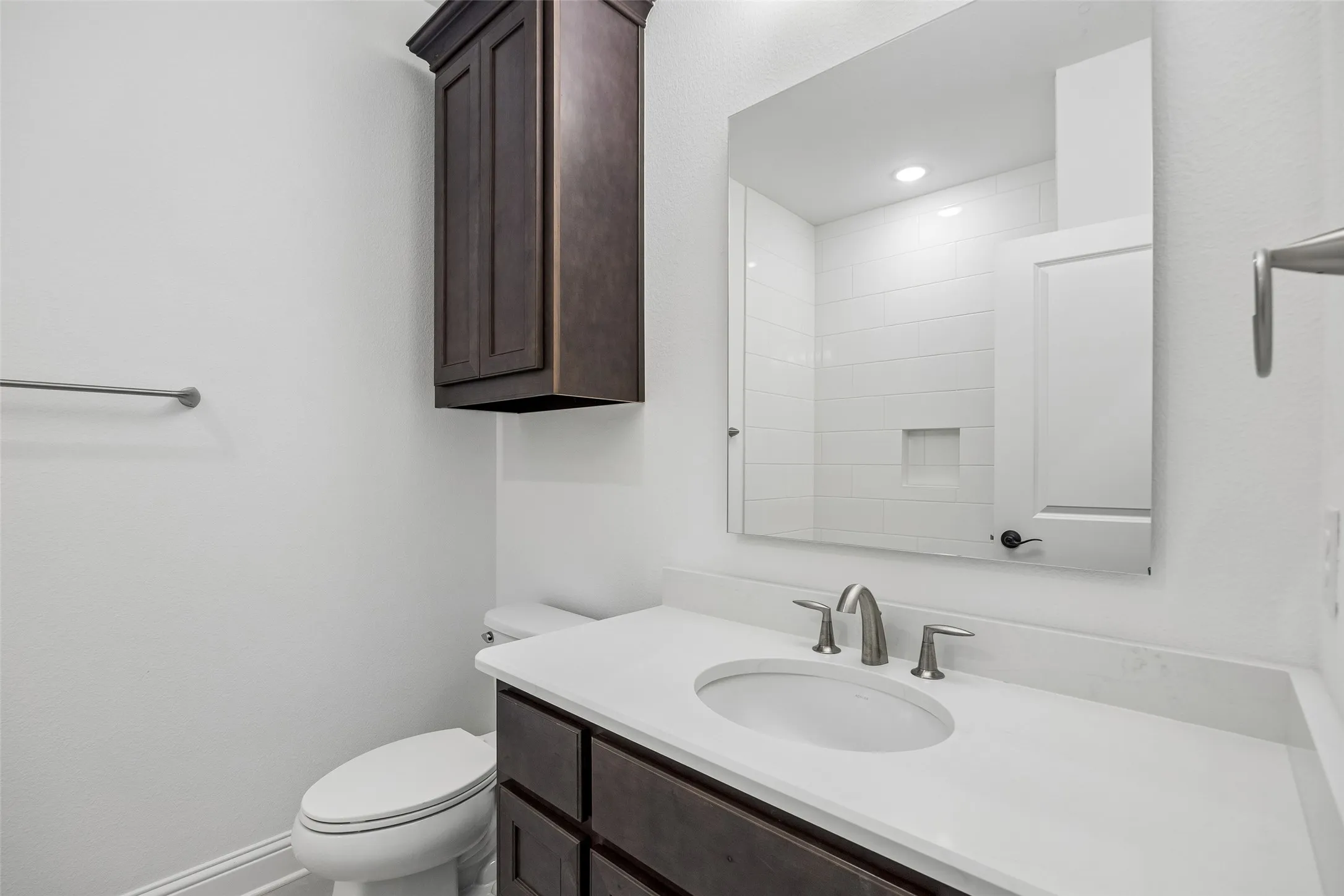 Built-in vanity with integrated sink, white countertop, and dark wood-finish cabinetry